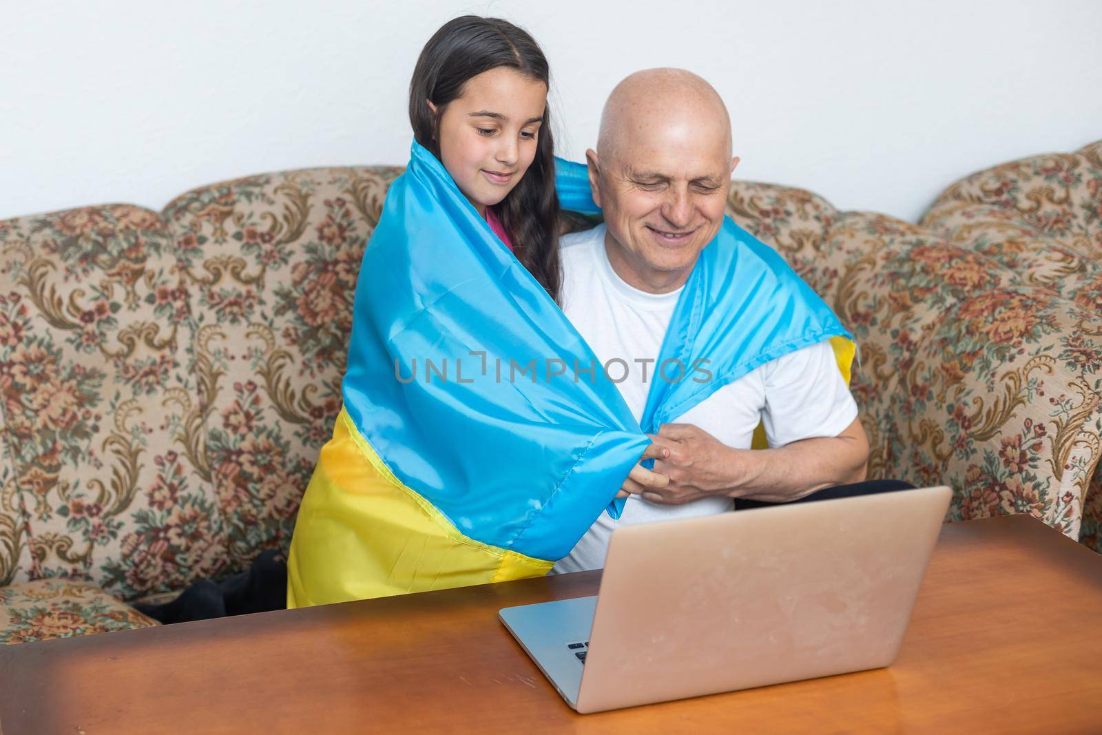 Grandfather and granddaughter with laptop and flag of Ukraine by Andelov13