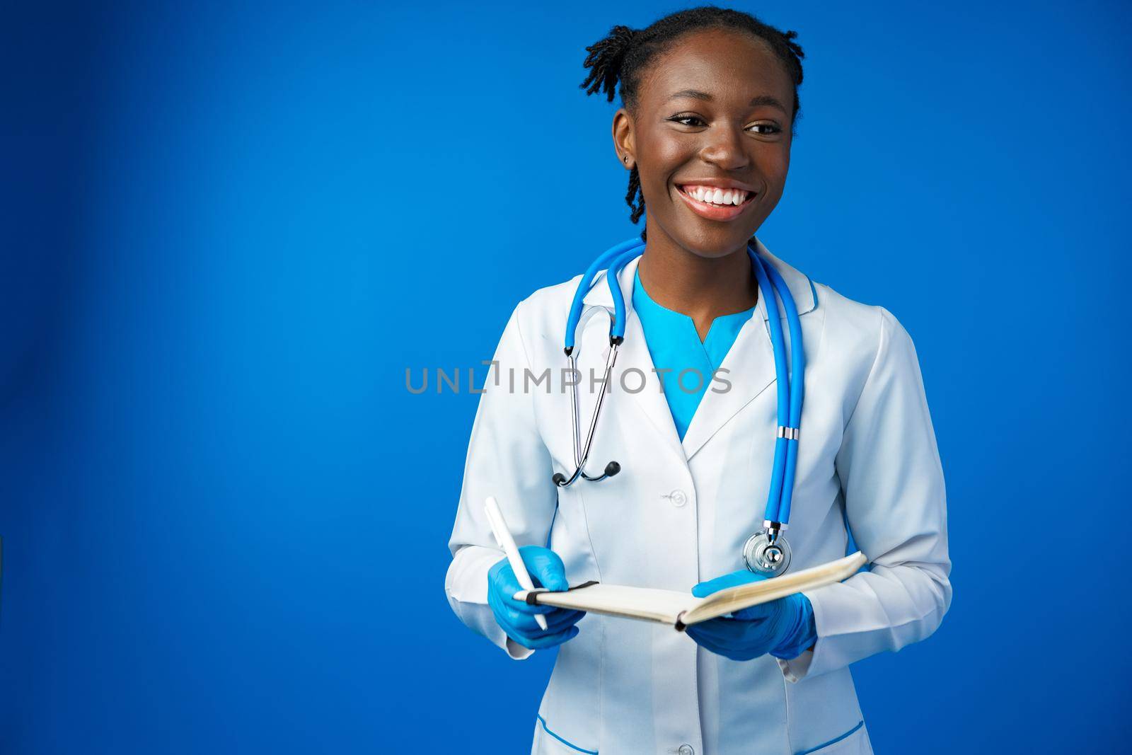 Black female doctor student wearing a lab coat with book in blue studio