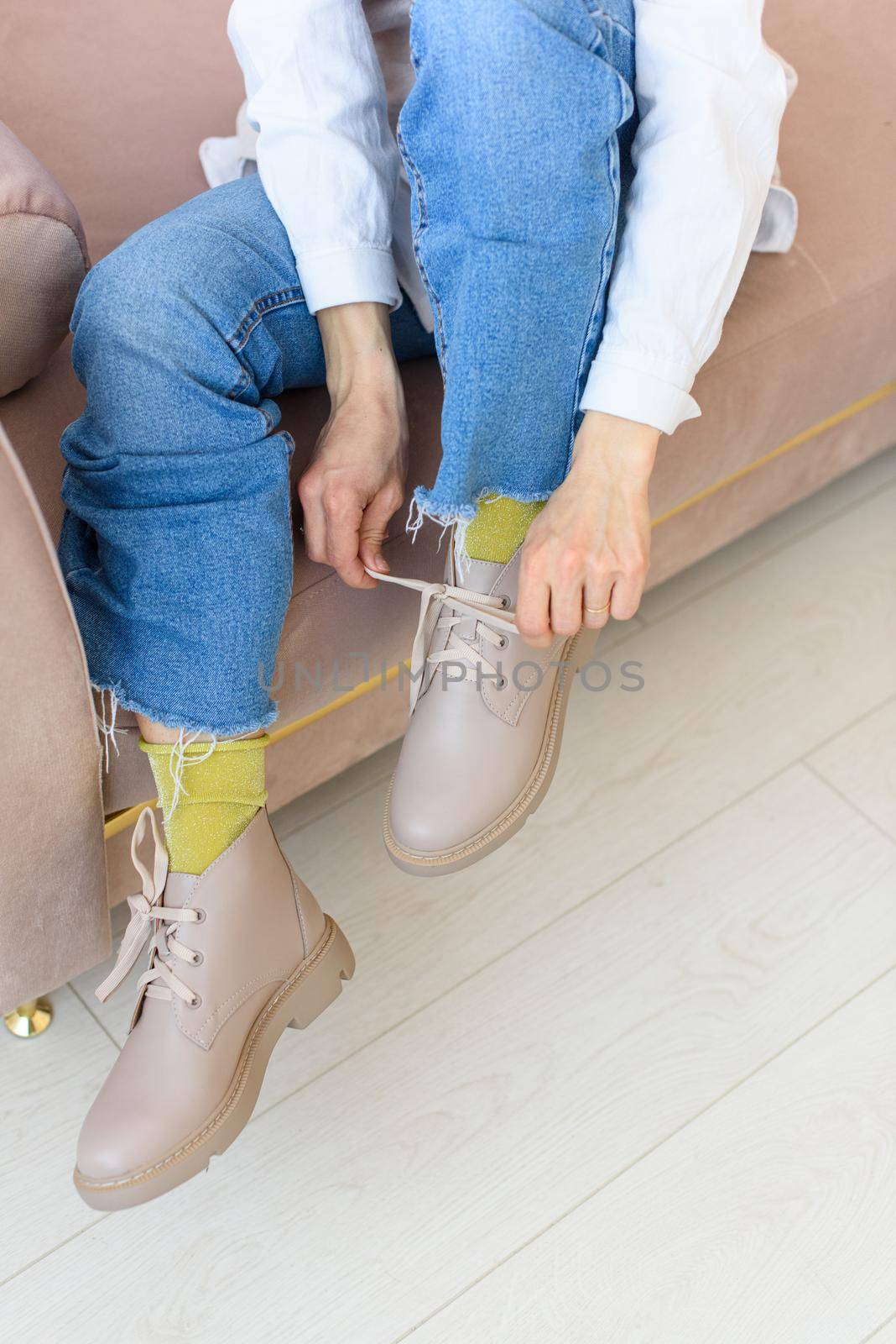 female legs in blue jeance and beige leather lace-up boots. Indoor photo.