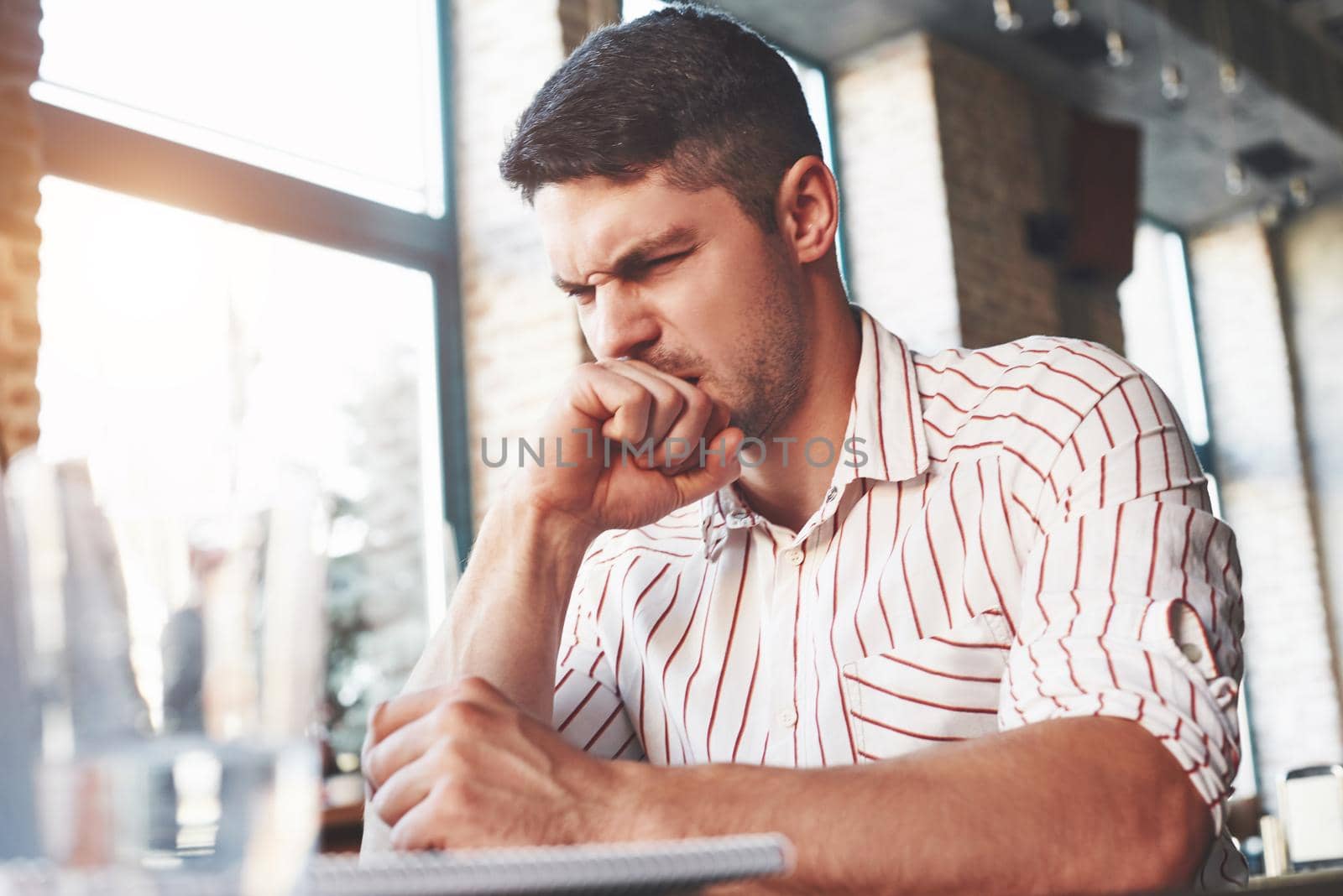 Looks like something wrong. Adult man sits in cafe at daytime and read some hard explained information.