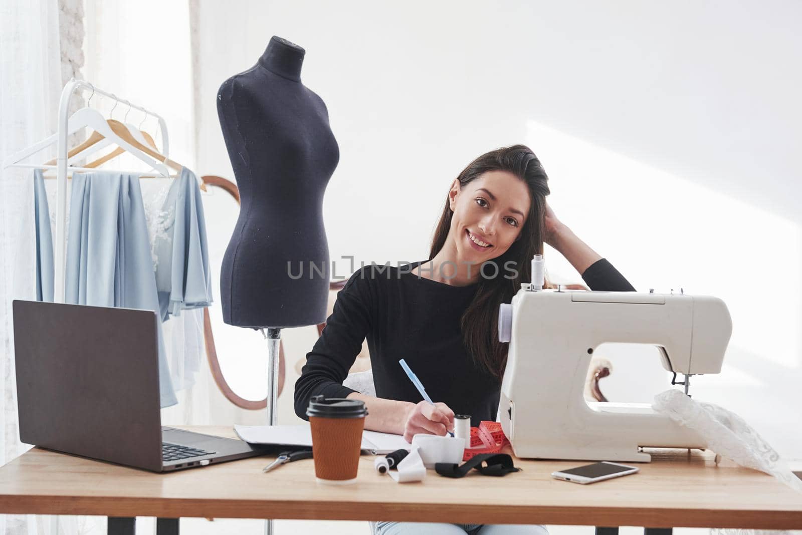 In love with her job. Female fashion designer works on the new clothes in the workshop.