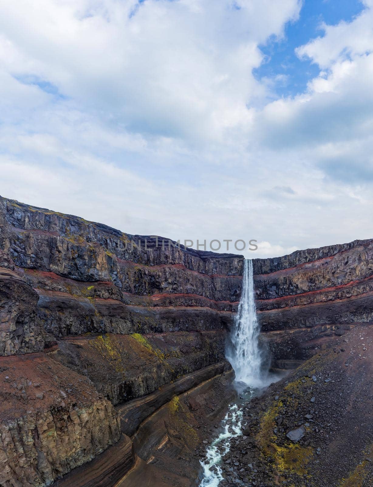 Hengifoss waterfall with red layers under cloudy sky by FerradalFCG