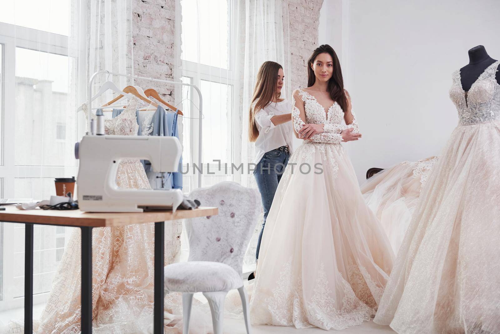 Helping the bride. The process of fitting the dress in the studio of hand crafted clothes.