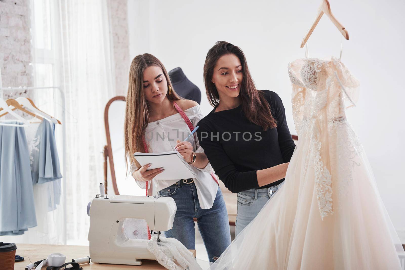 Two girls have maked good dress. The process of fitting the dress in the studio of hand crafted clothes.