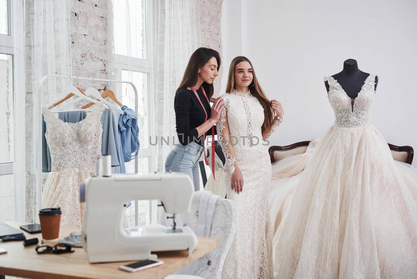 Woman is helping the girl. The process of fitting the dress in the studio of hand crafted clothes.