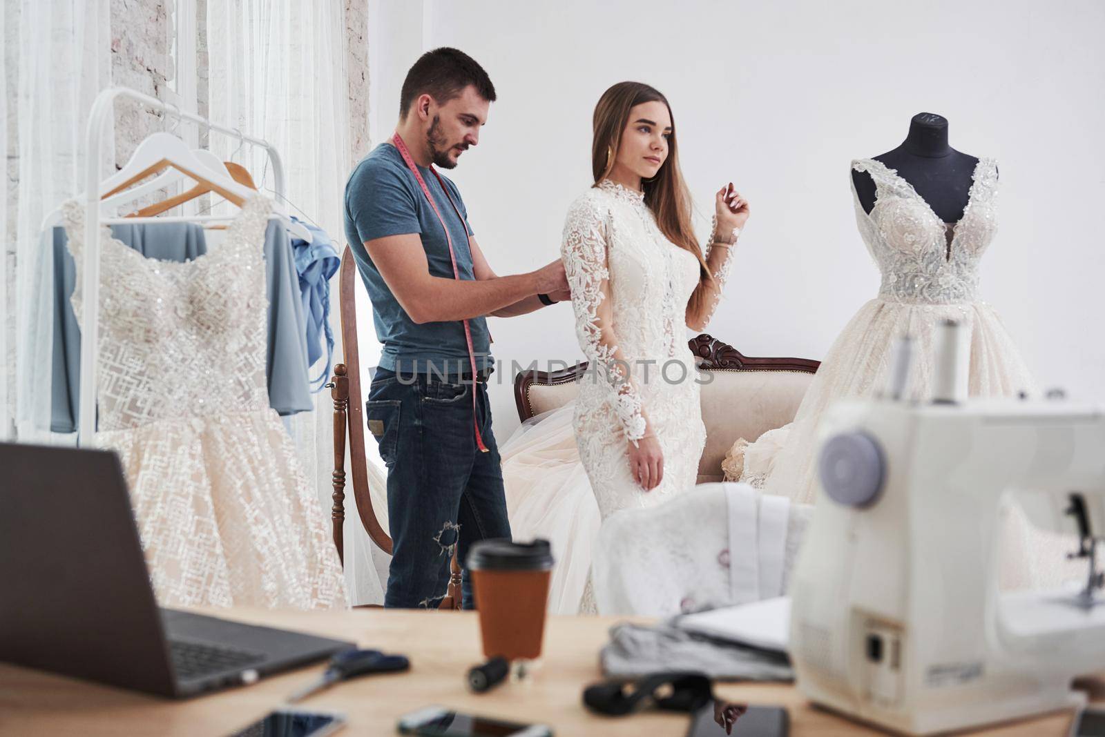 Guy helps the bride. The process of fitting the dress in the studio of hand crafted clothes.