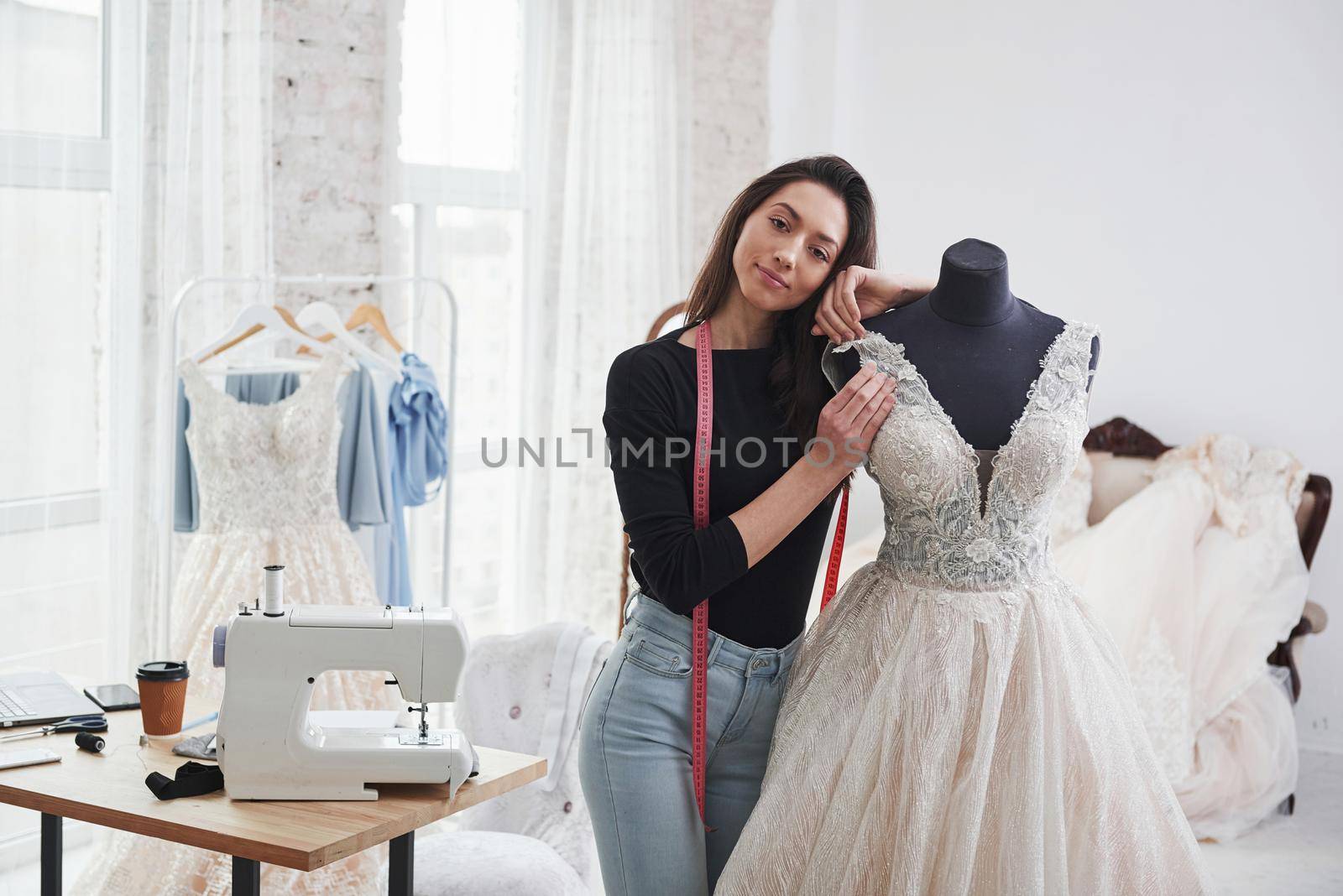 Leaning on the mannequin. Female fashion designer works on the new clothes in the workshop.