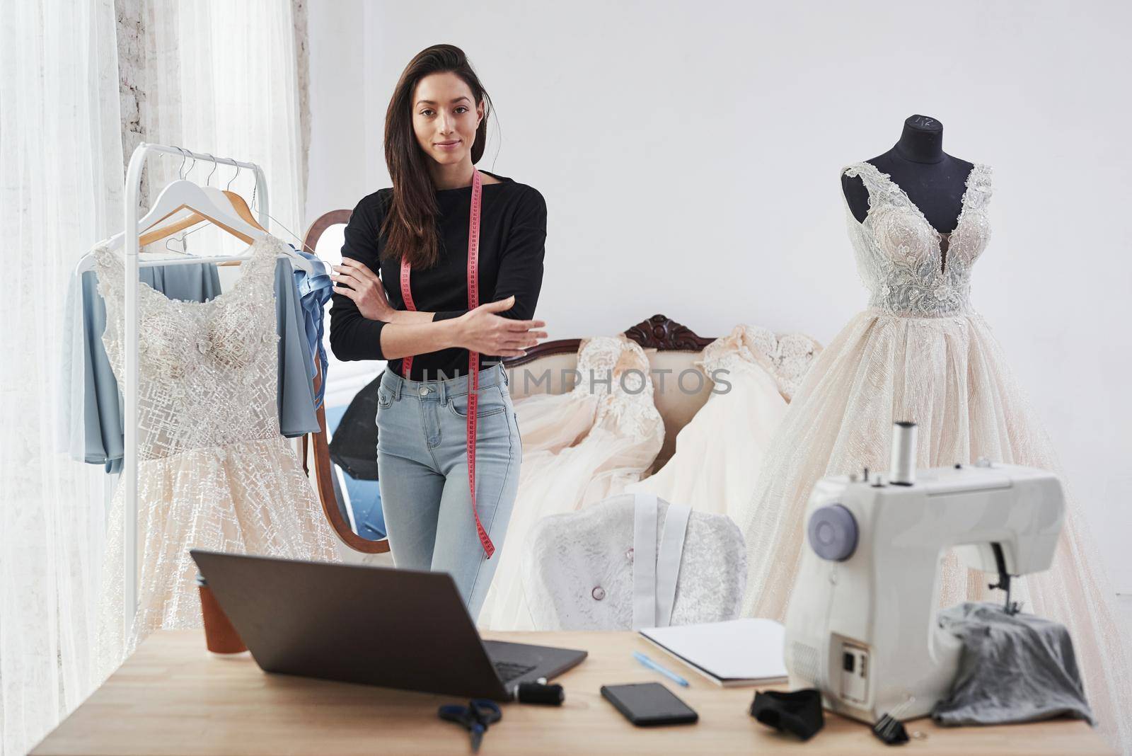 Proud owner. Female fashion designer works on the new clothes in the workshop.