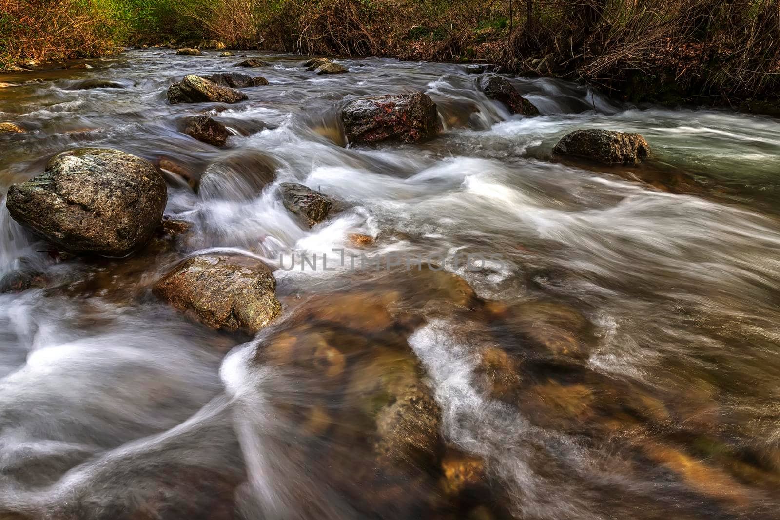 beautiful motion blur view of flowing water in the river with stones 