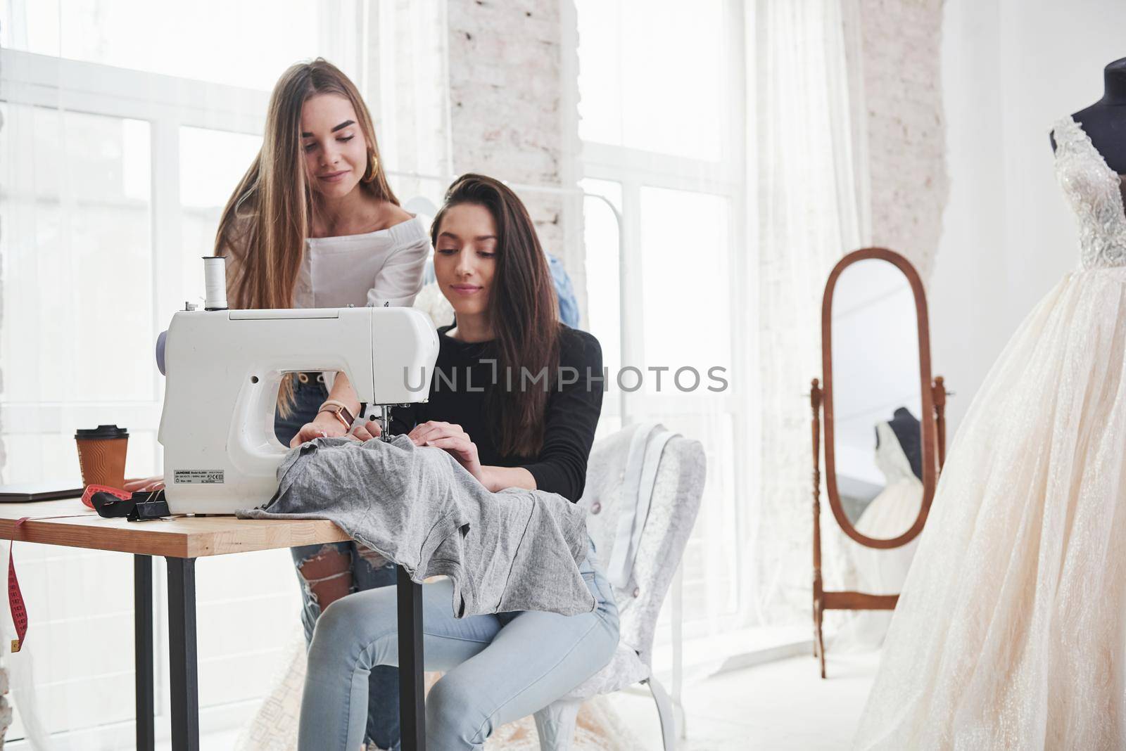 Calm mood. Two female fashion designers works on the new clothes in the workshop by Standret