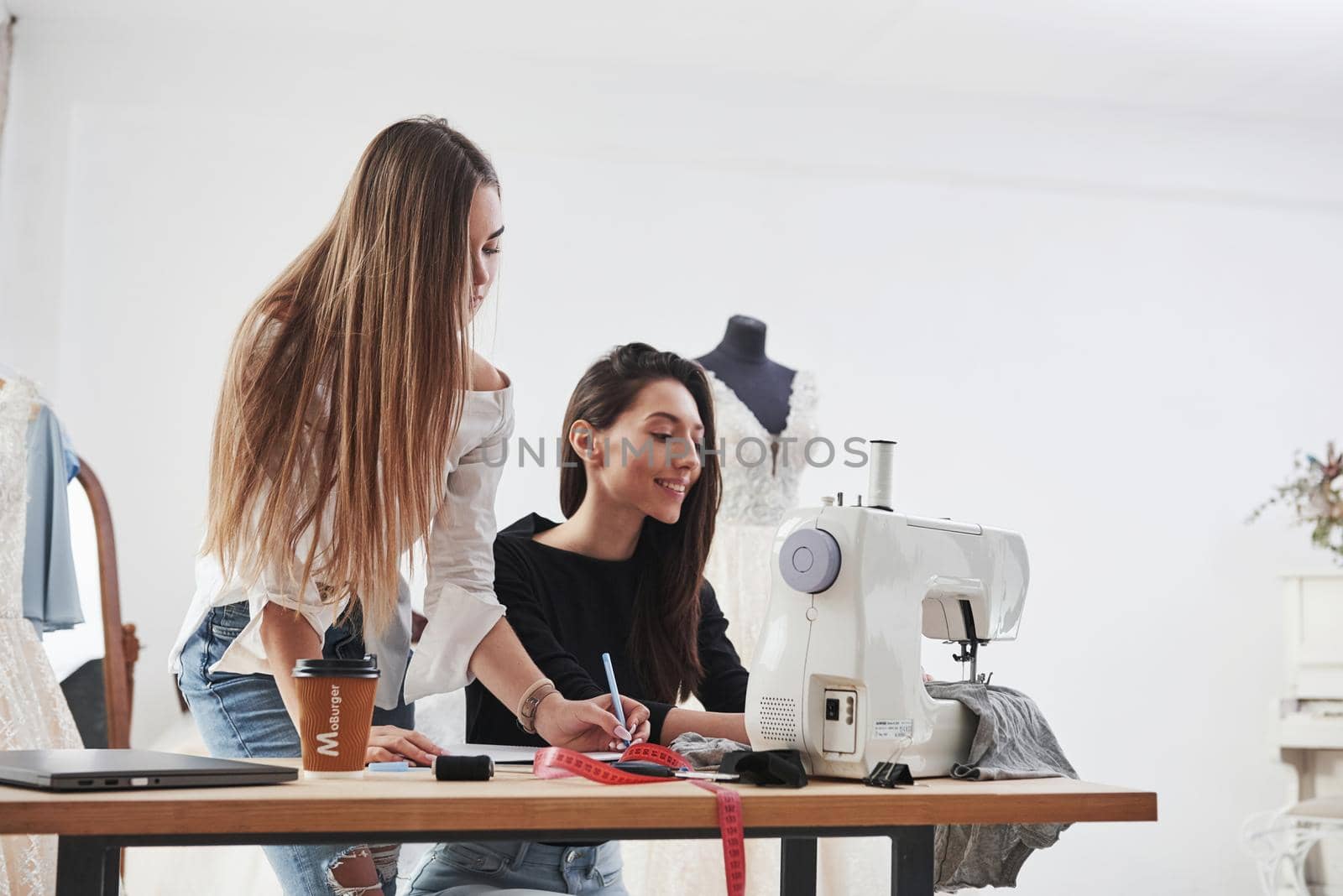 Our dress will be perfect. Two female fashion designers works on the new clothes in the workshop by Standret