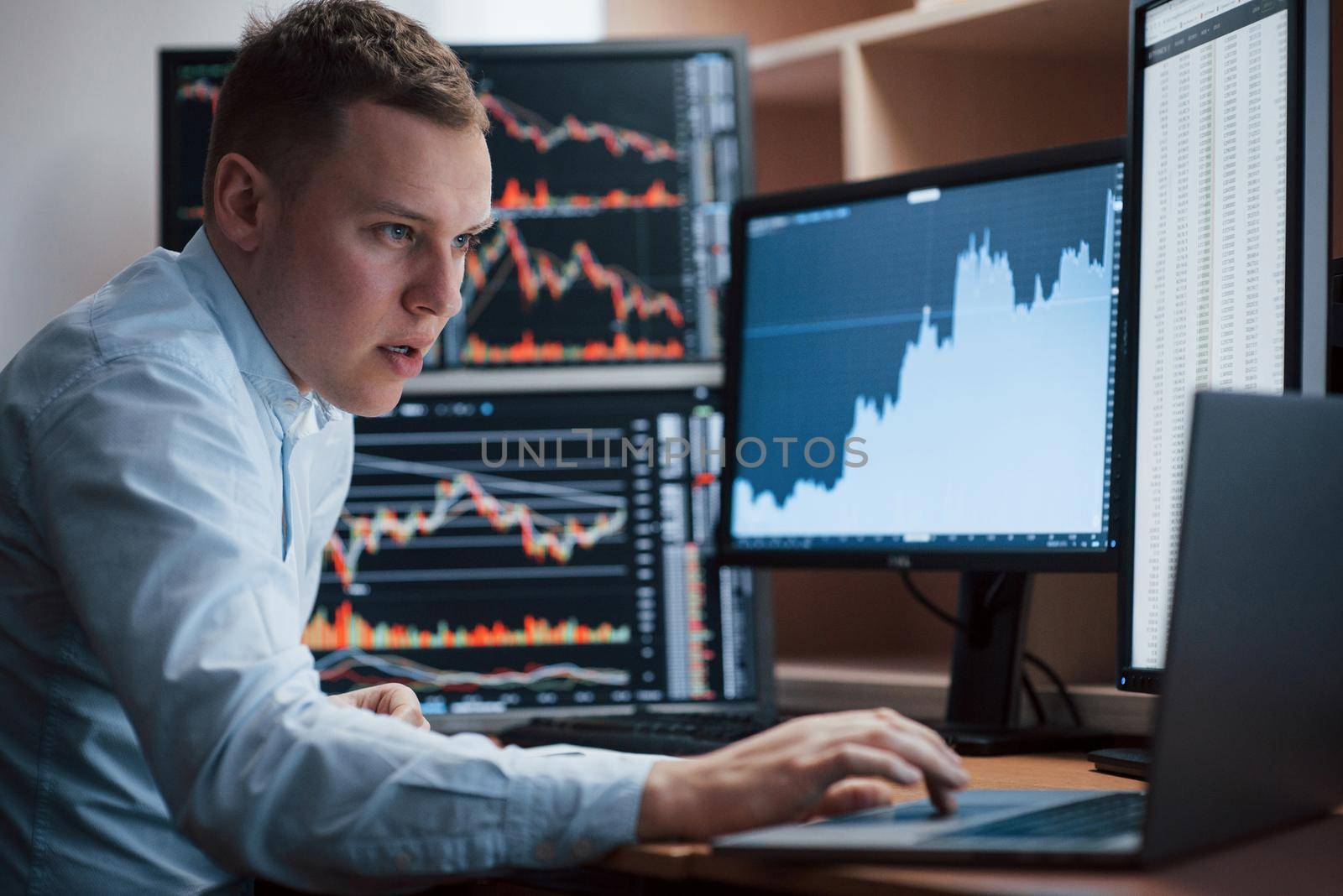 Thinks what to do next. Man working online in the office with multiple computer screens in index charts.