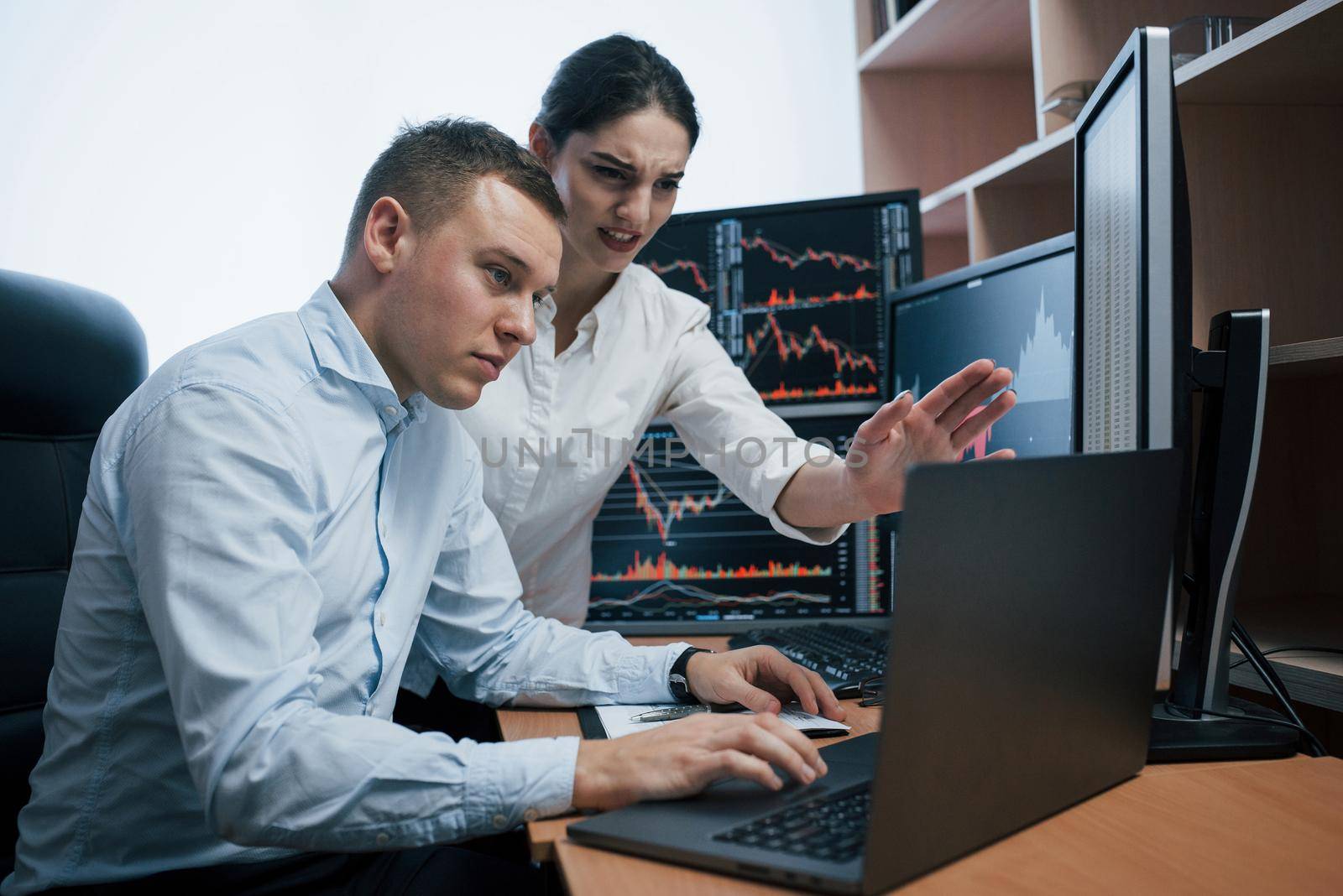 Team of stockbrokers are having a conversation in a office with multiple display screens.