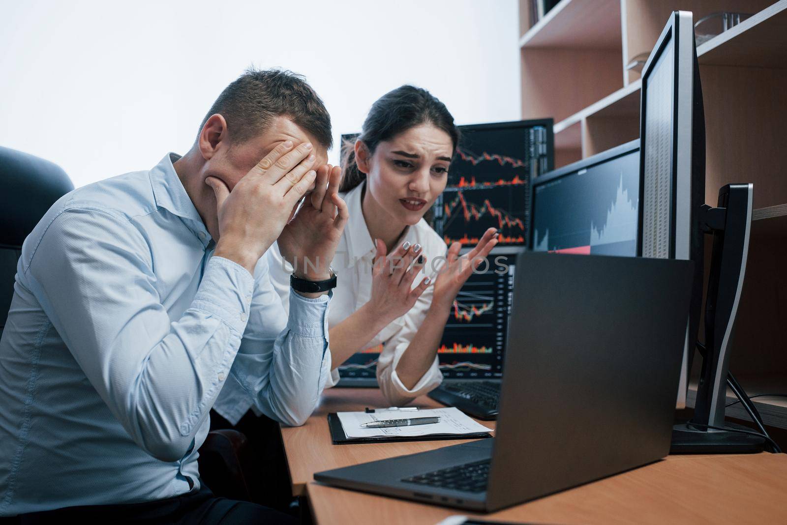 It's failure. Team of stockbrokers are having a conversation in a office with multiple display screens.