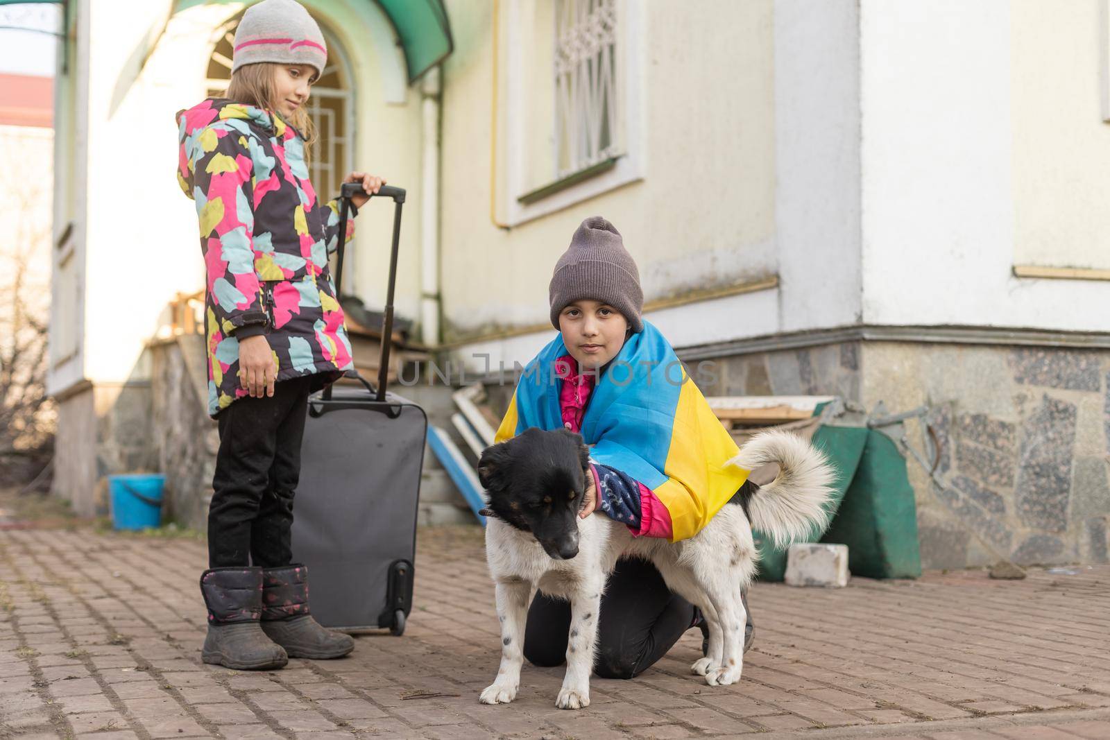 two little girls with the flag of ukraine, suitcase, dogs. Ukraine war migration. Collection of things in a suitcase. Flag of Ukraine, help. Krizin, military conflict