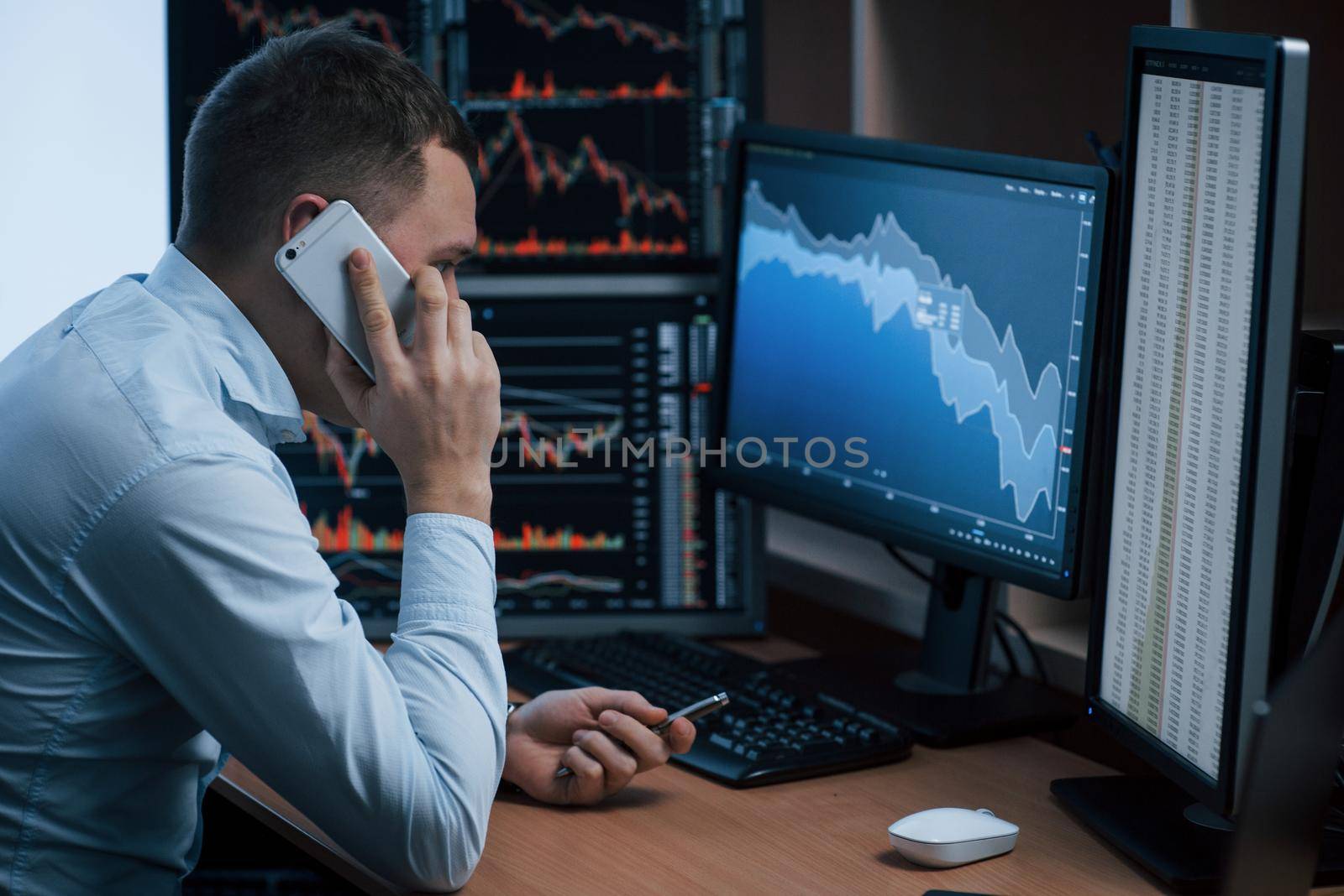 Alone in the room. Man working online in the office with multiple computer screens in index charts.