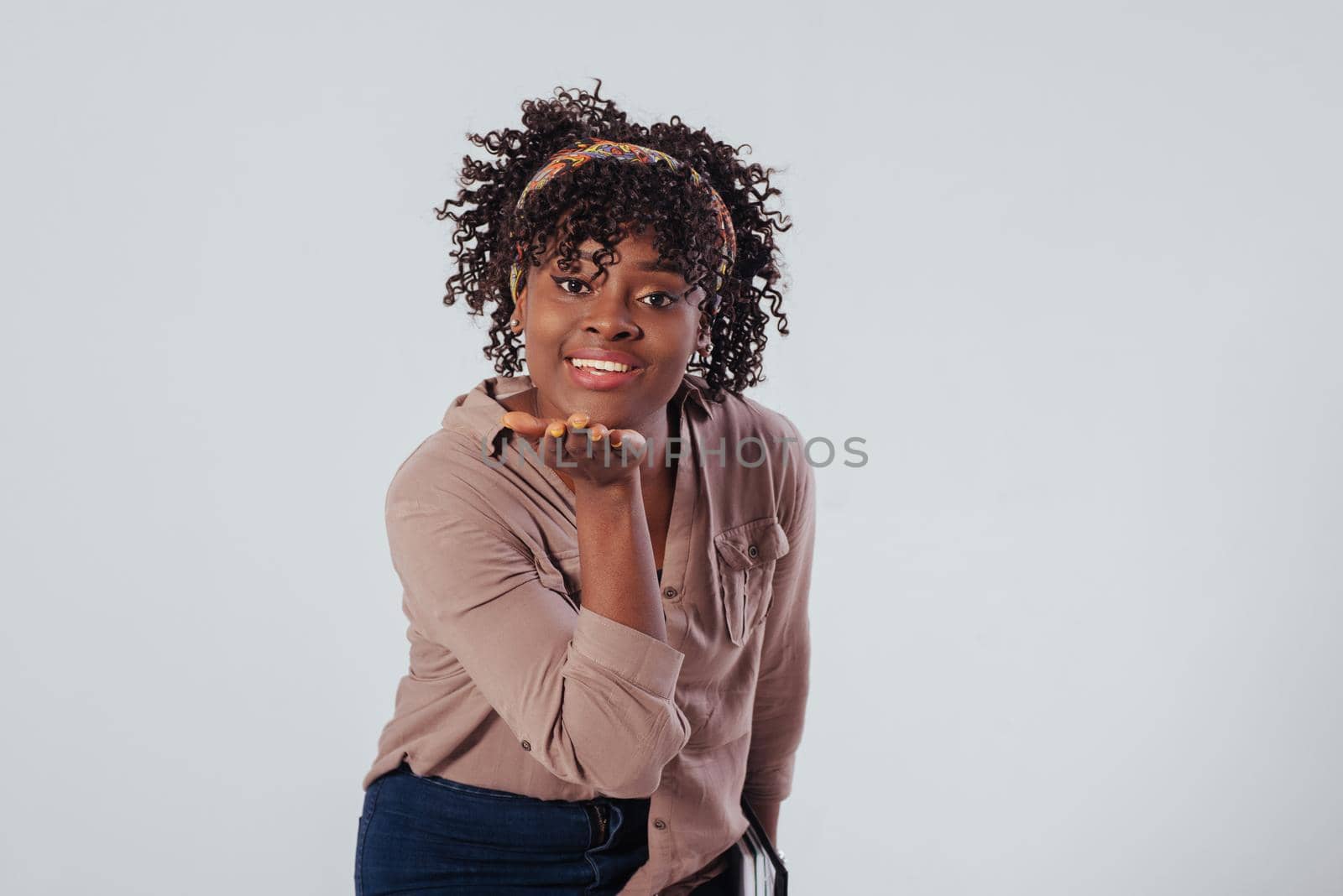 It's air kiss for you. Beautiful afro american girl with curly hair in the studio with white background.