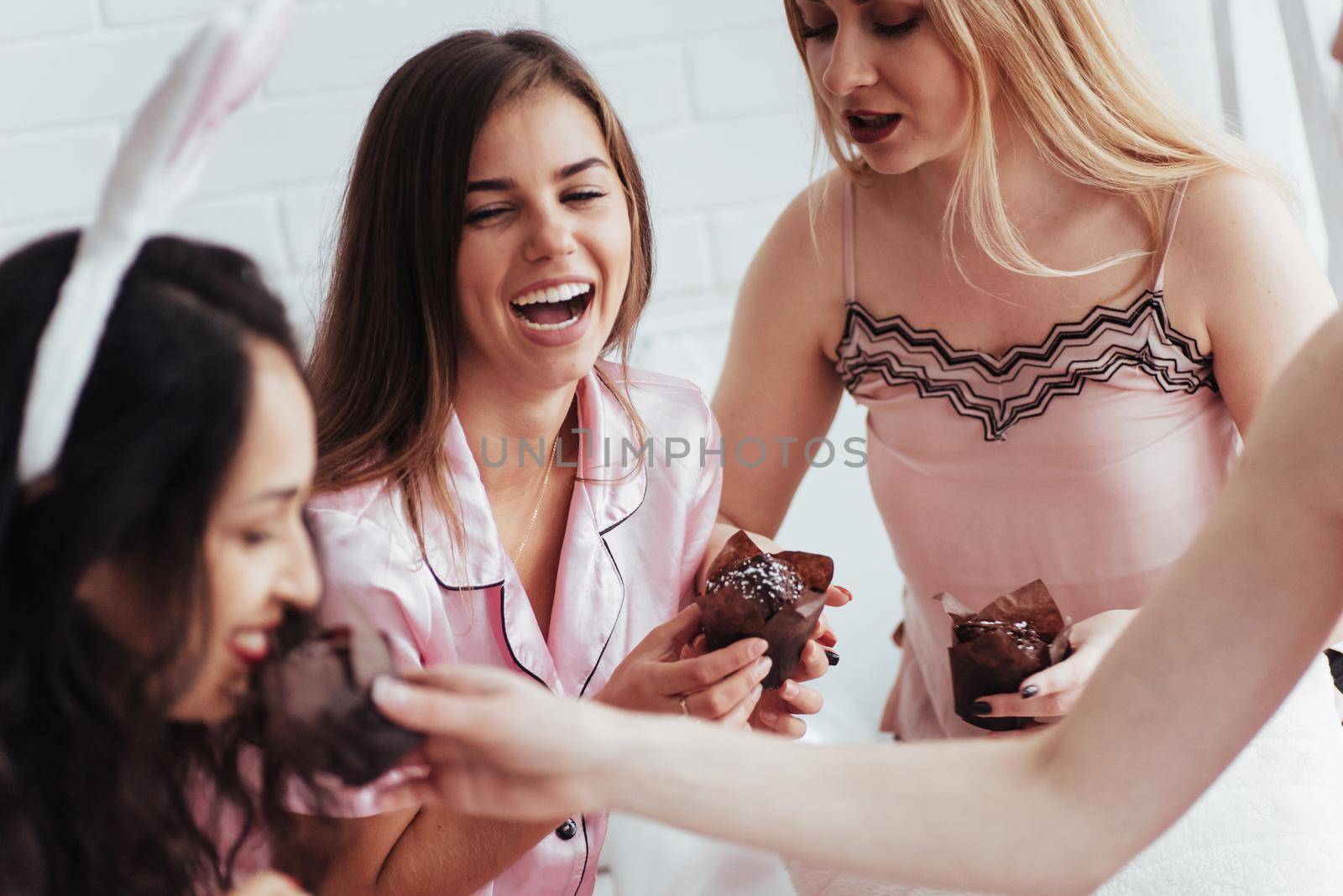 Always together. Bachelorette party in the bedroom. Delicious looking chocolate cookies at the girlish day. Four women in night wear.