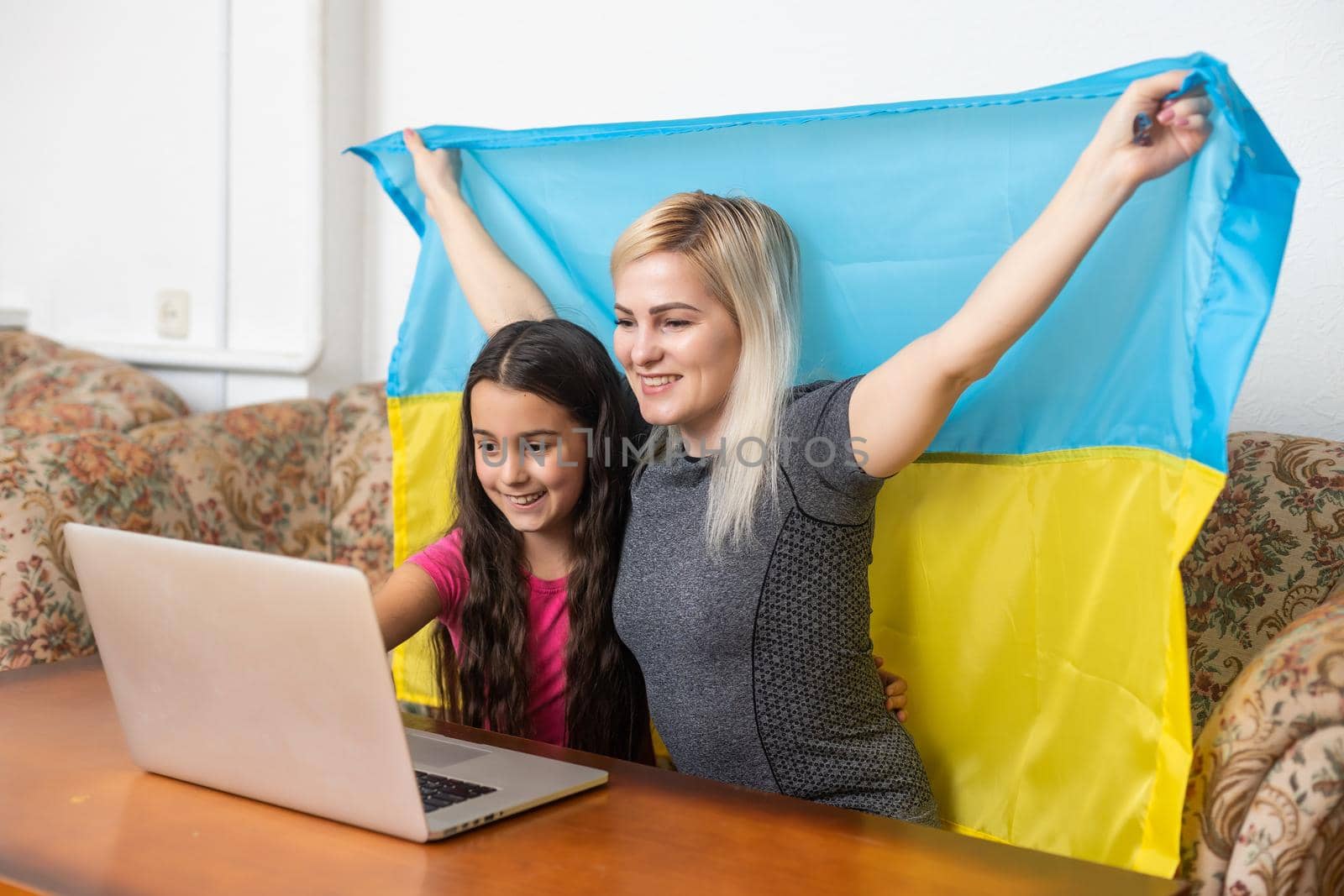 Online Digital Media Support For Ukraine. Freedom And Patriotism Concept. mother and daughter with laptop and ukraine flag.