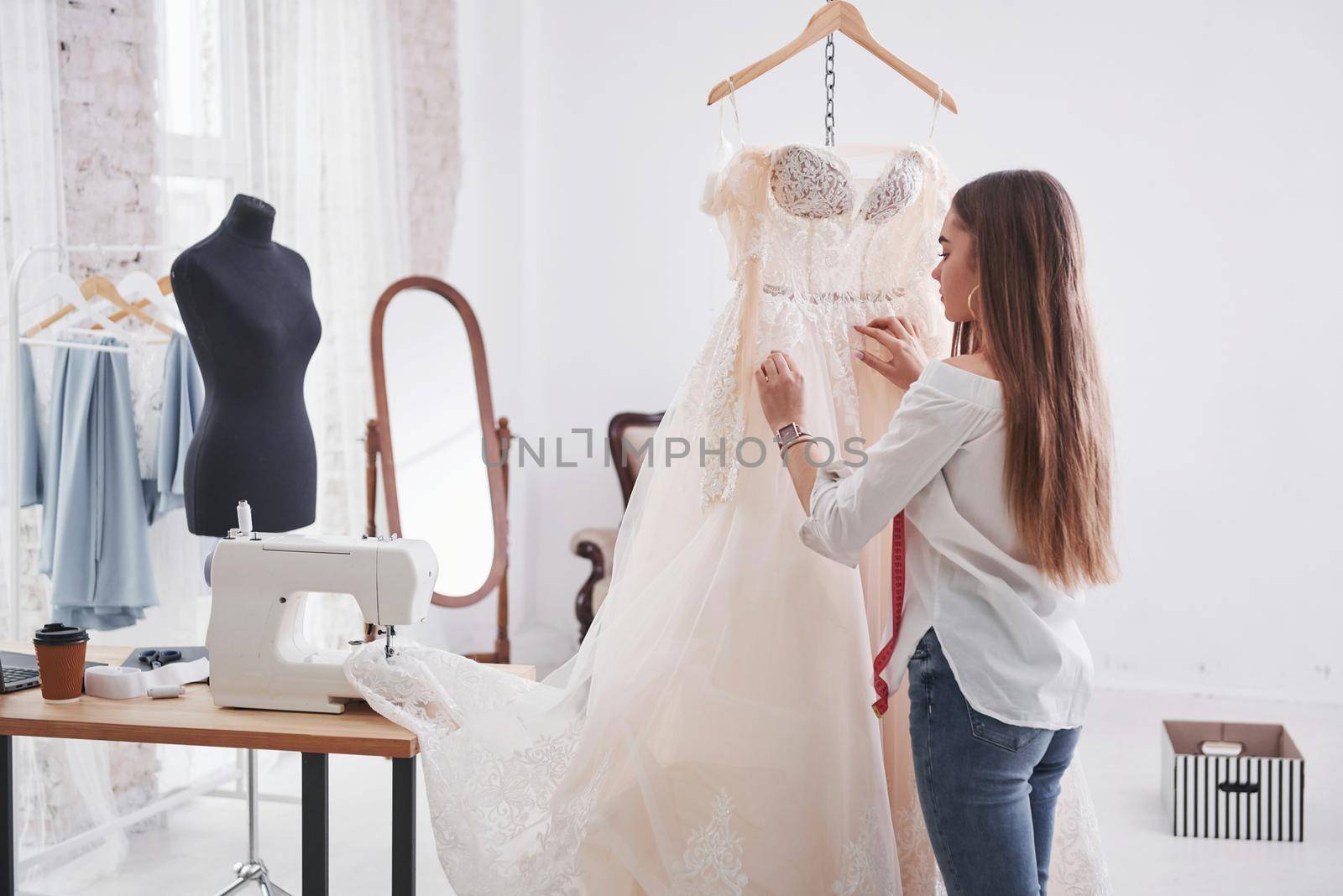 Creating beautiful dress. Female fashion designer works on the new clothes in the workshop.