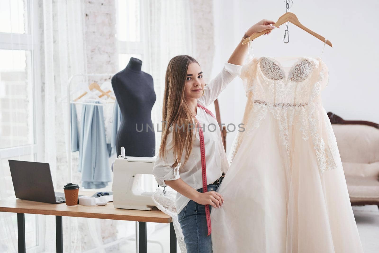 Showing the results. Female fashion designer works on the new clothes in the workshop.