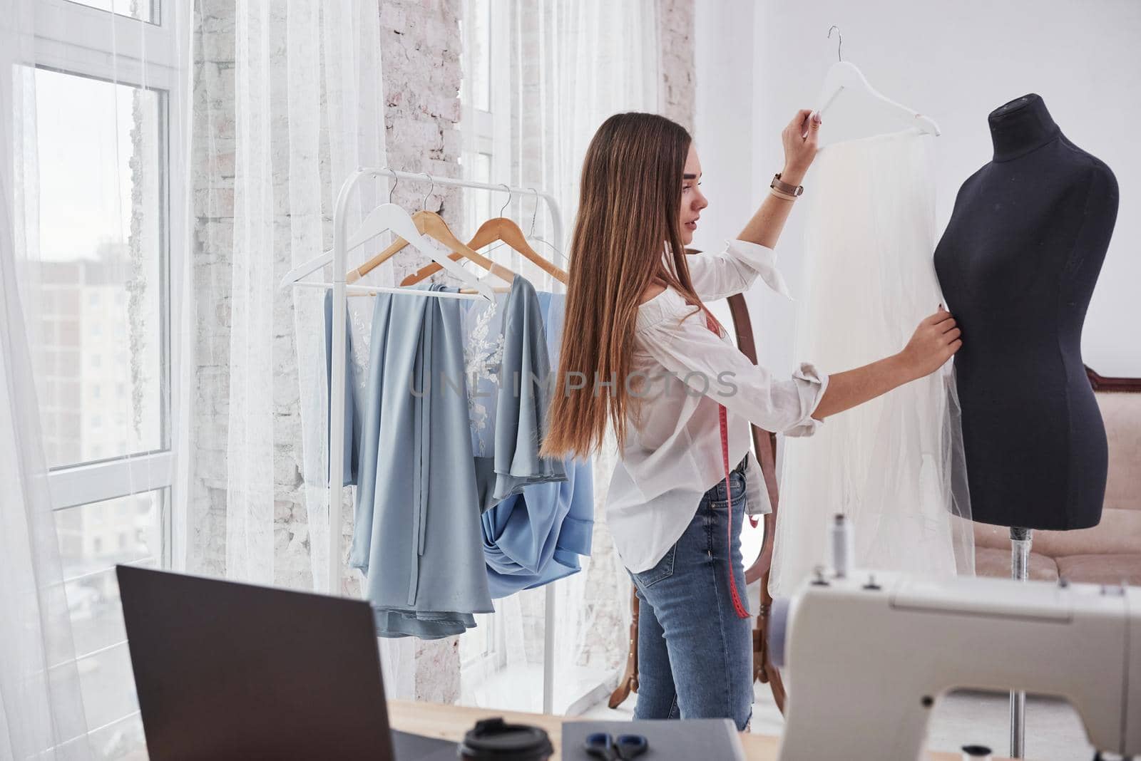 Adjusts the size. Female fashion designer works on the new clothes in the workshop.