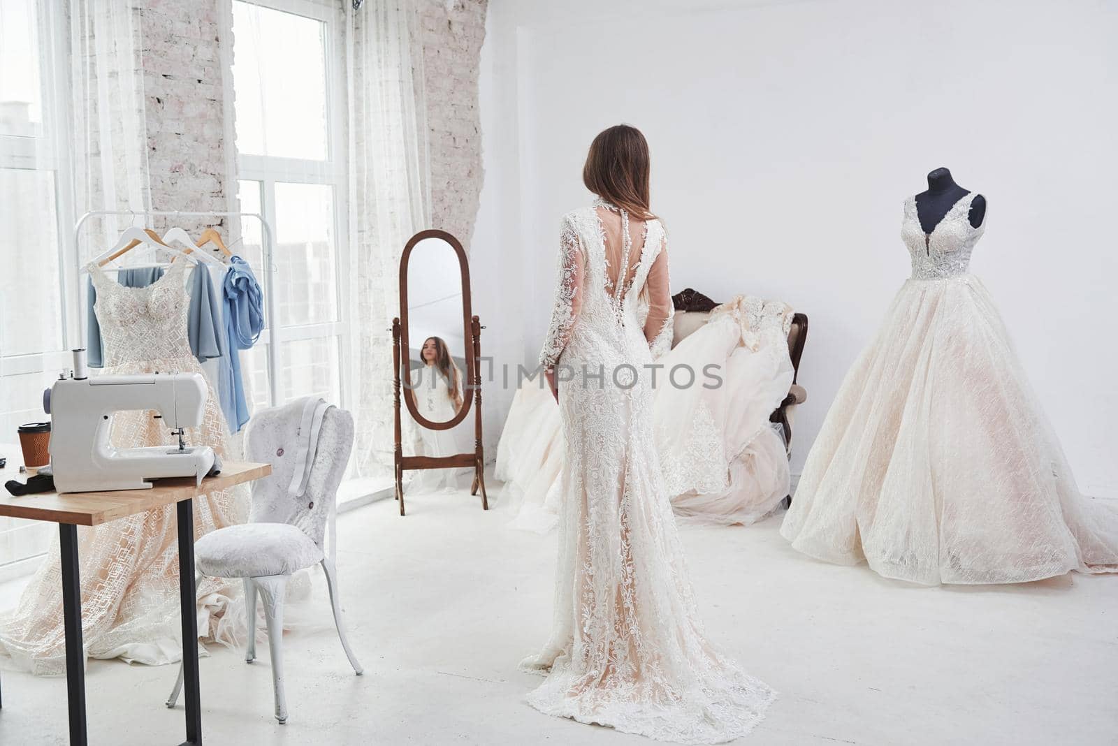 Showing back and looking in the mirror. The process of fitting the dress in the studio of hand crafted clothes.