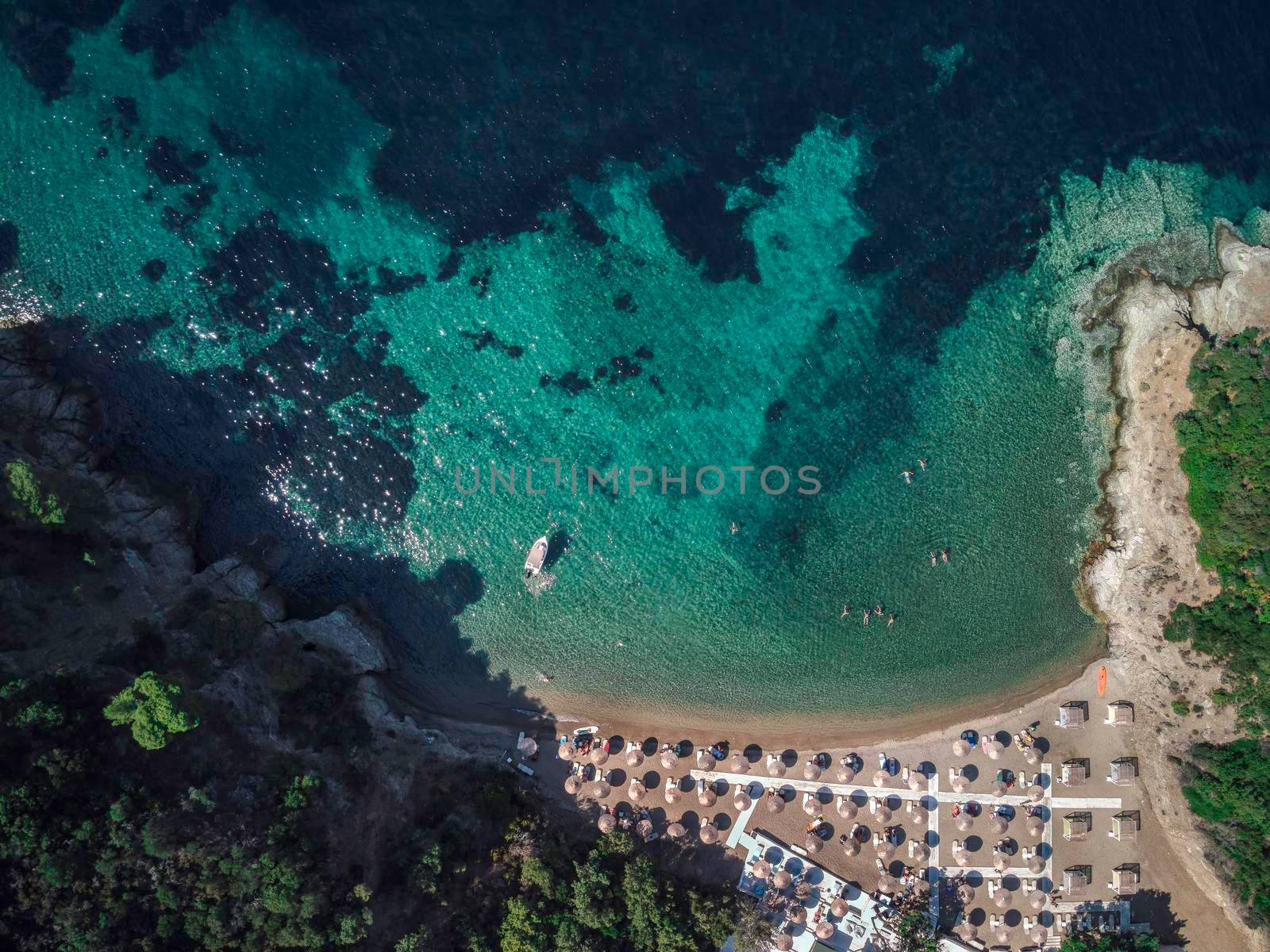 Turquoise water Mediterranean beach with sea umbrellas aerial drone view in Sithonia Chalkidiki peninsula Greece.