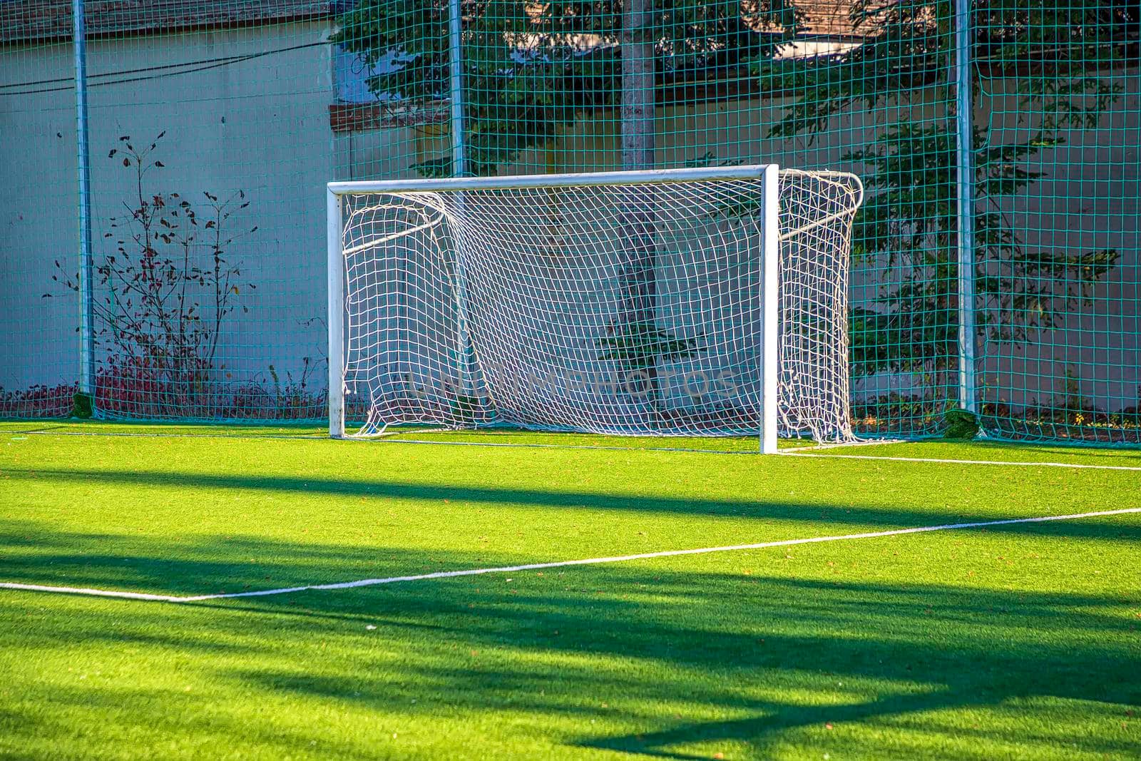 Empty white gate on the football field with green grass. Concept of training in football sections and schools, preparation for competitions and matches. by EdVal