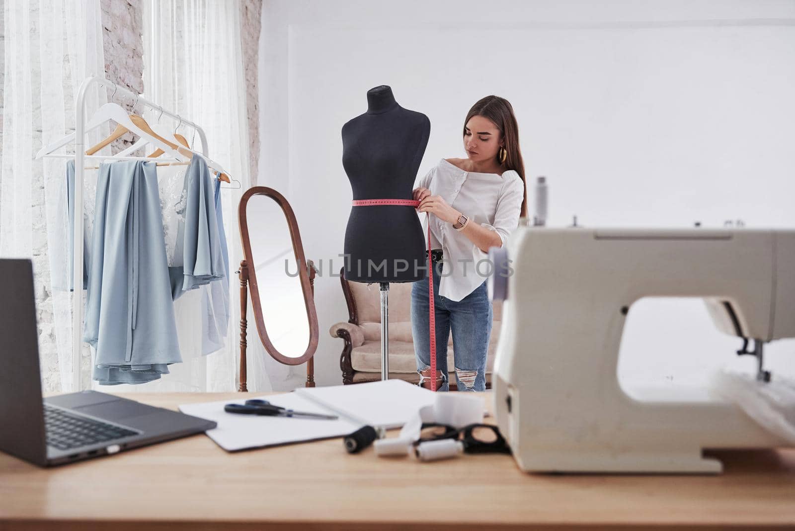 Pink measure tape around mannequins waist. Female fashion designer works on the new clothes in the workshop.