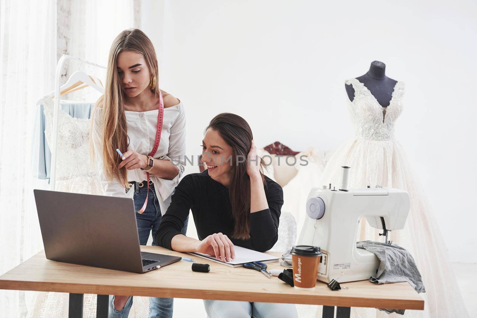 Together doing her good their good job. Two female fashion designers works on the new clothes in the workshop by Standret