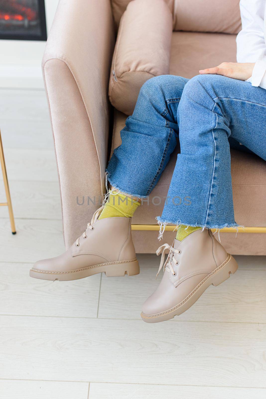 female legs in blue jeance and beige leather lace-up boots. Indoor photo.