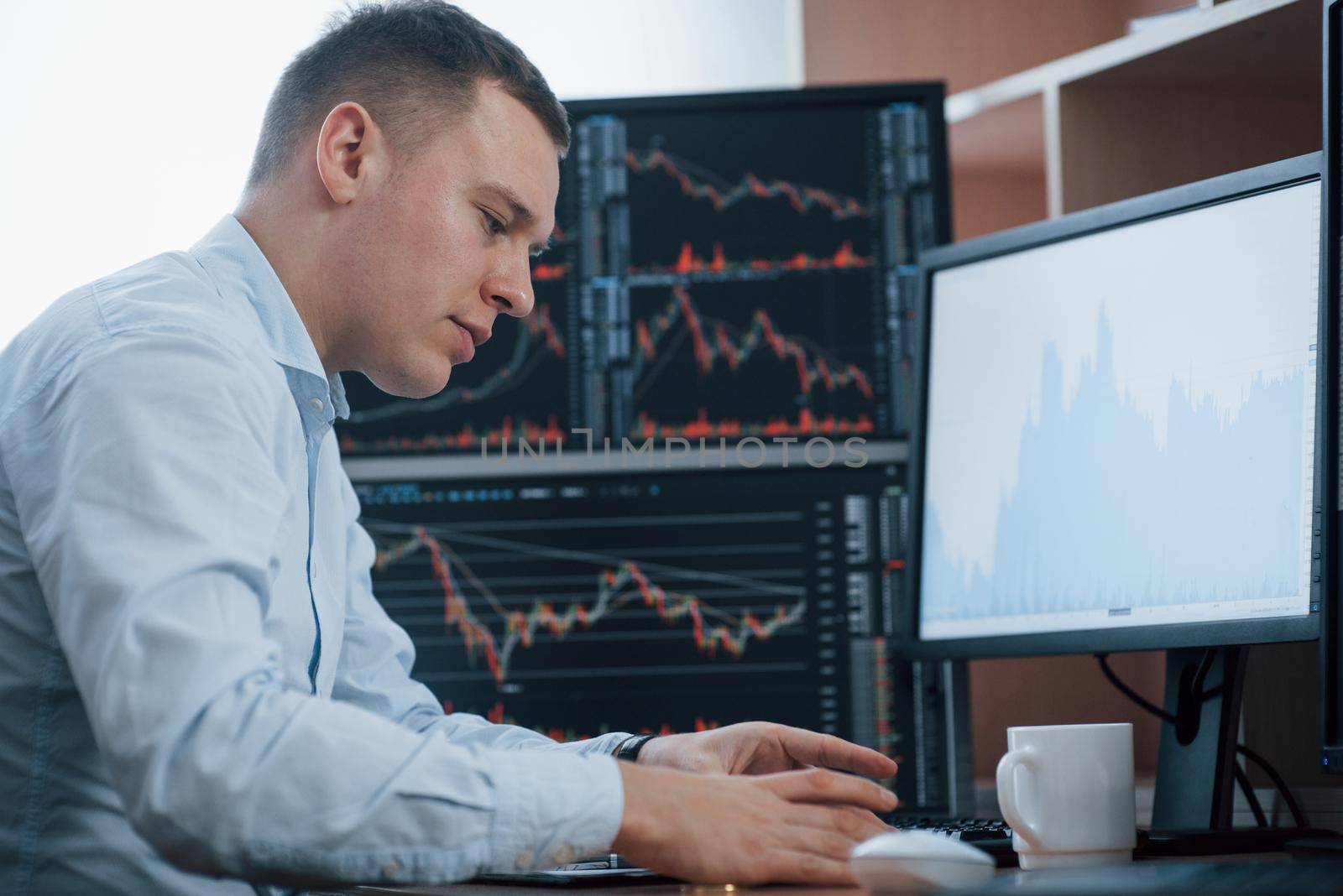 Man working online in the office with multiple computer screens in index charts.
