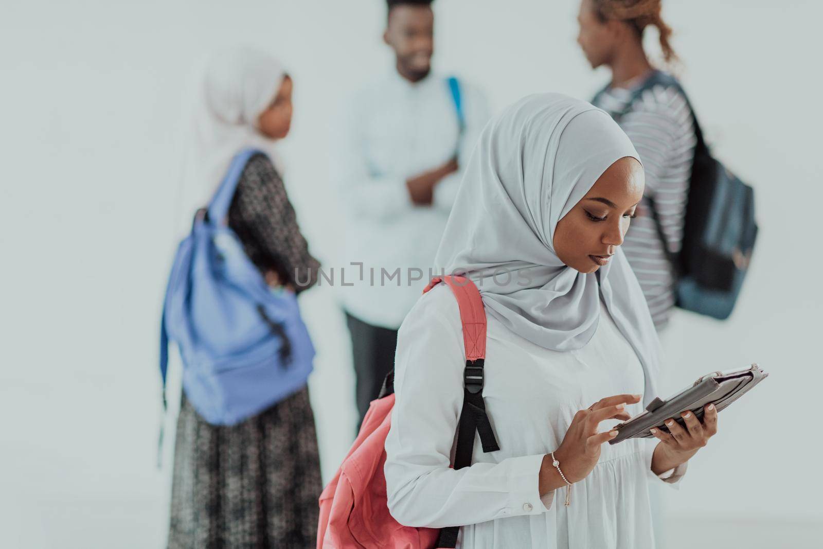 African female student with a group of friends in the background wearing traditional Islamic hijab clothes. Selective focus. High-quality photo