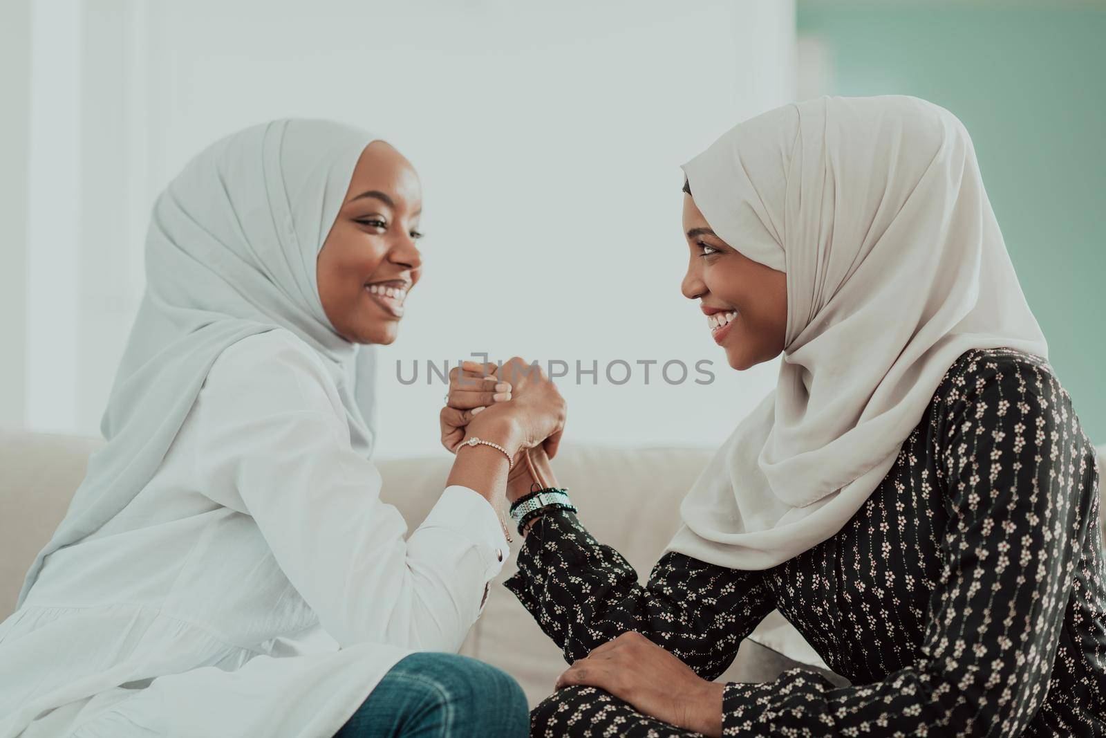 African woman arm wrestling conflict concept, disagreement and confrontation wearing traditional islamic hijab clothes. Selective focus by dotshock