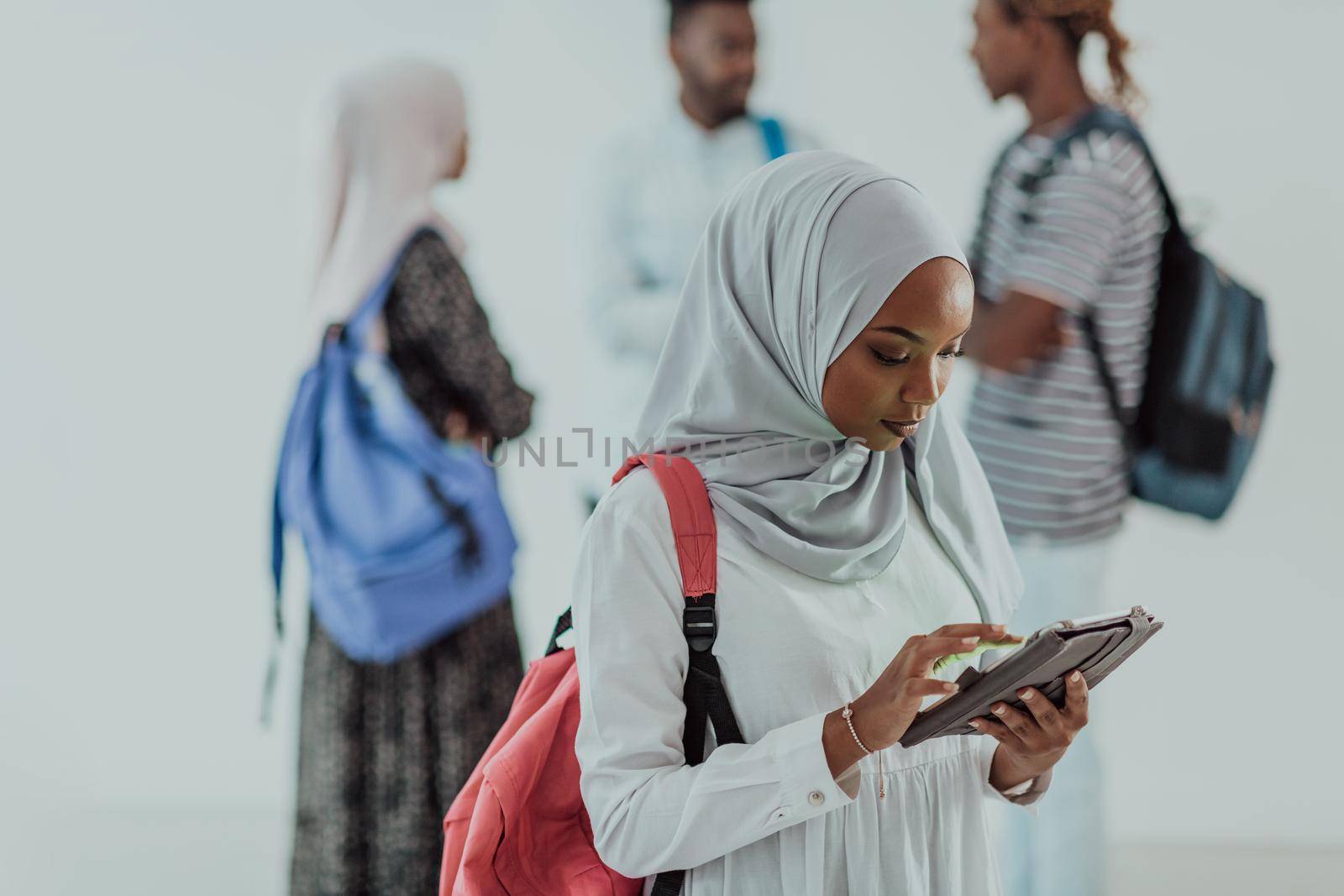 African female student with group of friends in background wearing traditional Islamic hijab clothes. Selectve focus by dotshock