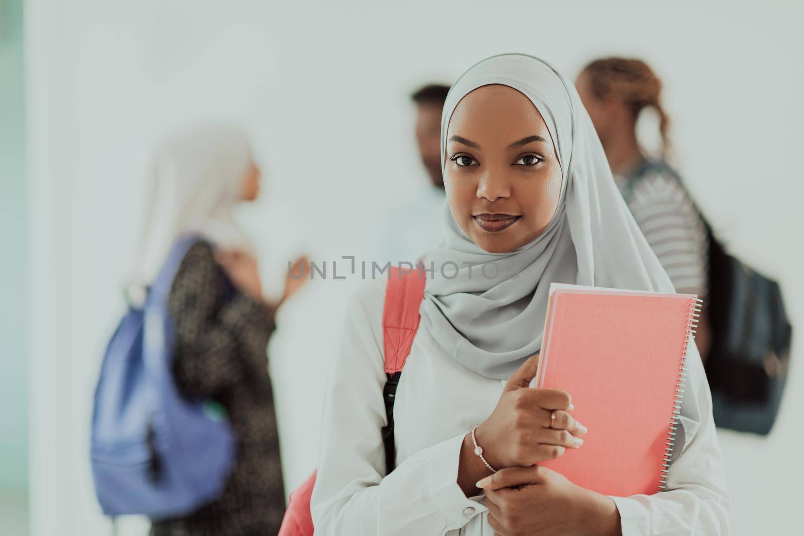 African female student with a group of friends in the background wearing traditional Islamic hijab clothes. Selective focus. High-quality photo