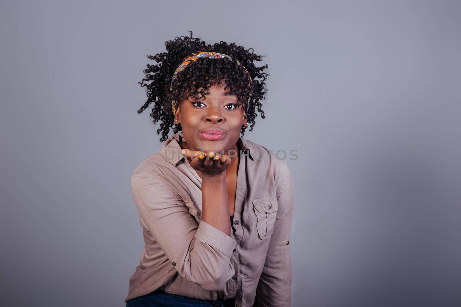 Giving air kiss. Attractive afro american woman in casual clothes in the studio.