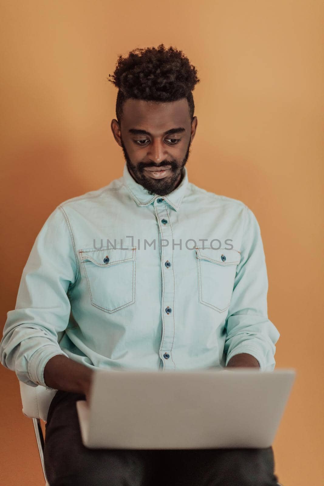 African student using laptop computer to study and make business connections yellow background. High quality photo