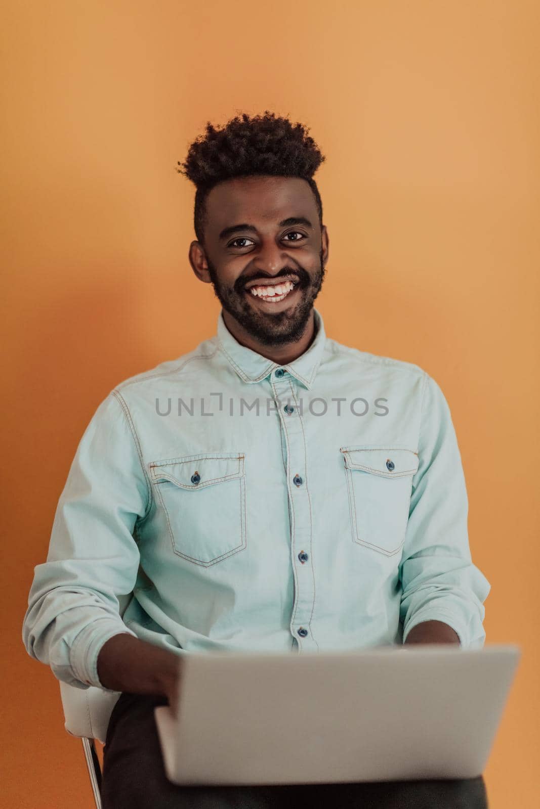 African student using laptop computer to study and make business connections yellow background. High quality photo