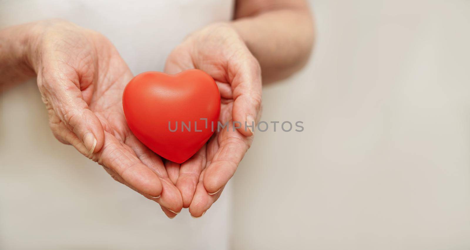 Grandmother woman hands holding red heart, healthcare, love, organ donation, mindfulness, wellbeing, family insurance and CSR concept, world heart day, world health day, national organ donor day.