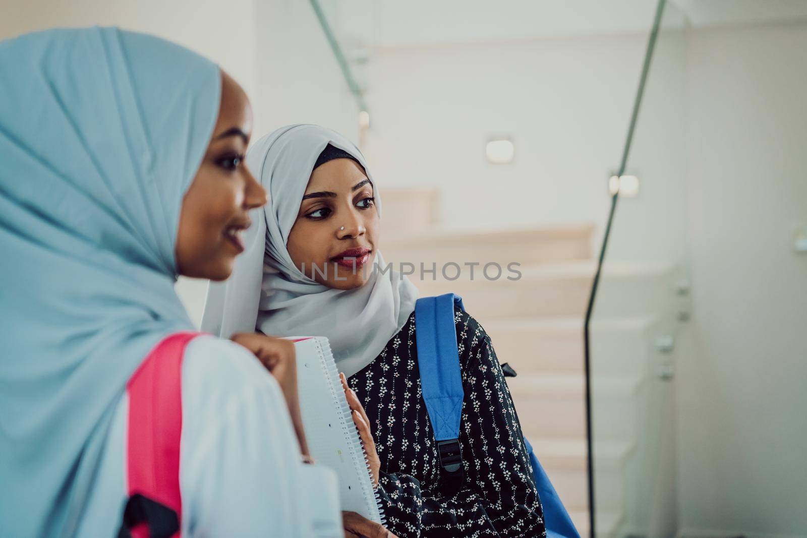 A photo of two african muslim female students with a backpack on their backs in a modern house. by dotshock