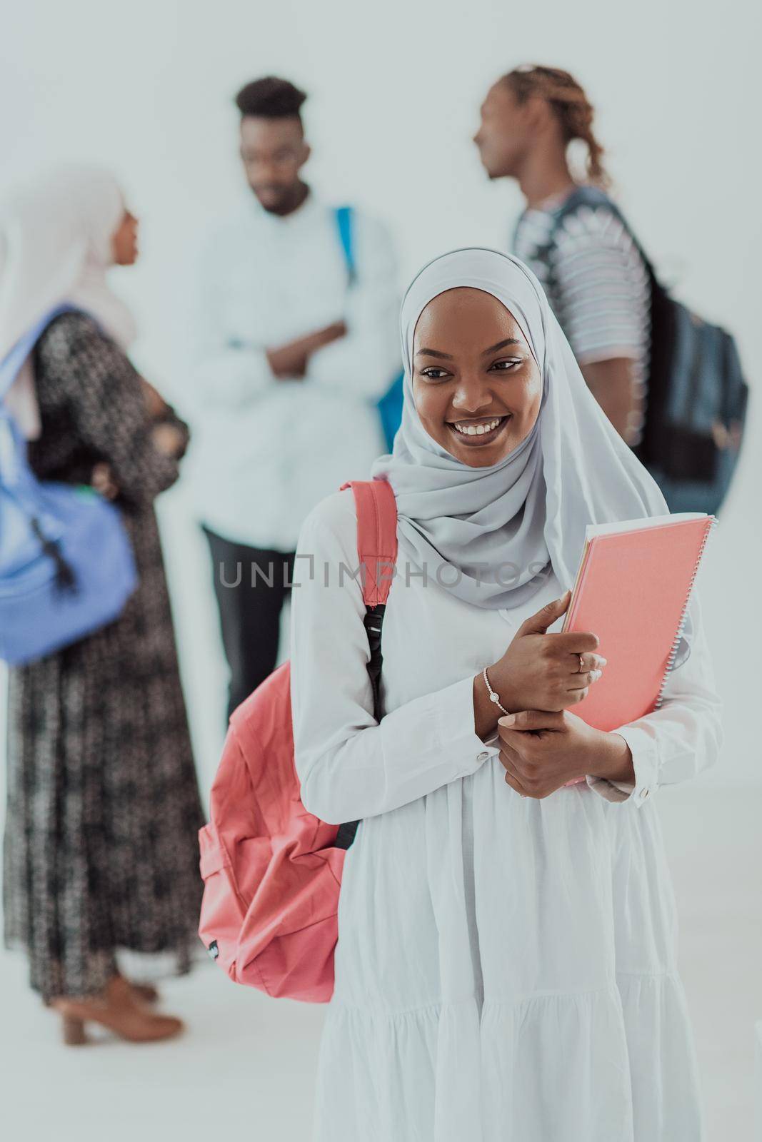 African female student with group of friends in background wearing traditional Islamic hijab clothes. Selectve focus by dotshock