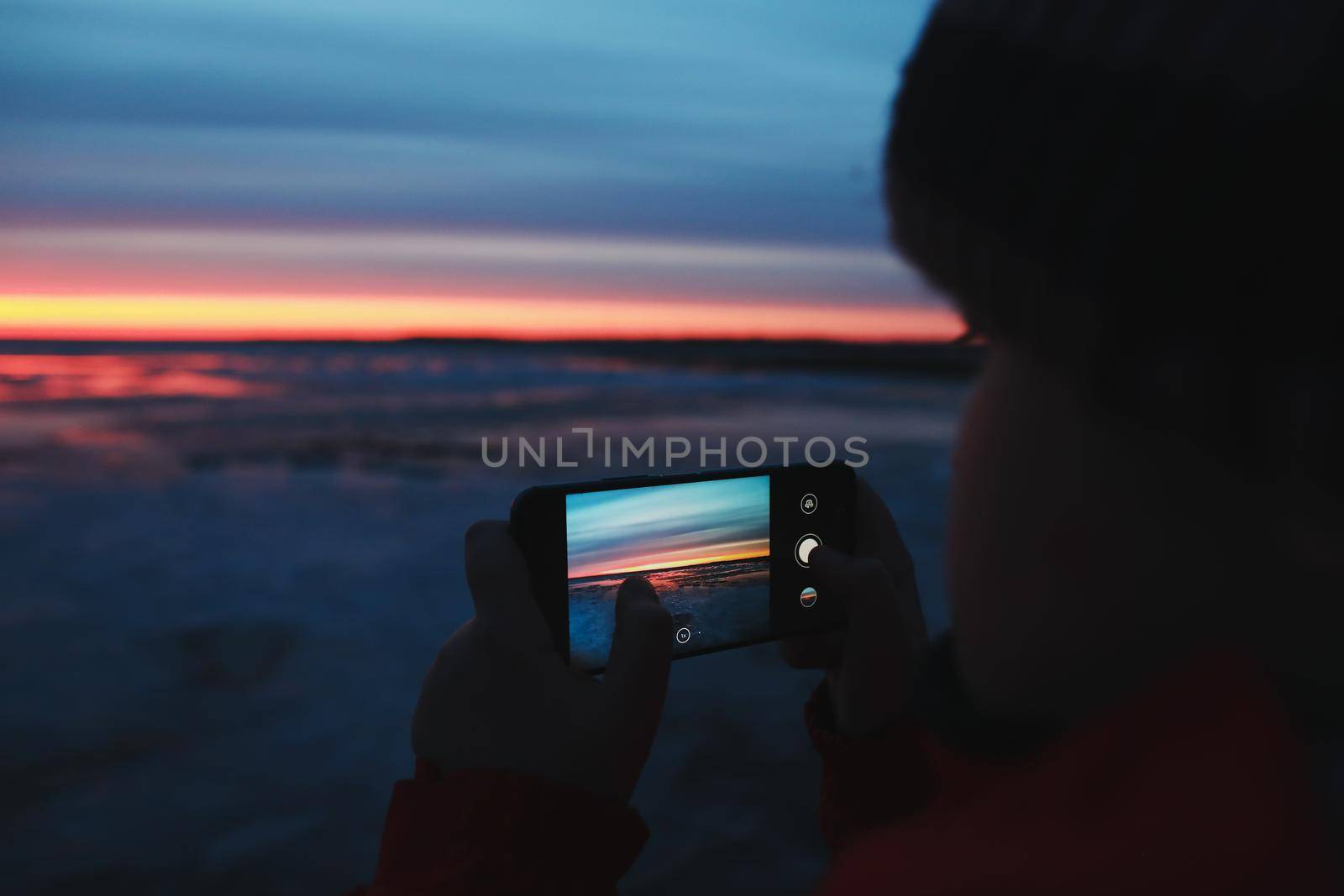 Man hands with mobile cell phone taking a photo of sunset sky at sea. Gradient color. Sky texture. Beautiful abstract nature sunset as background.