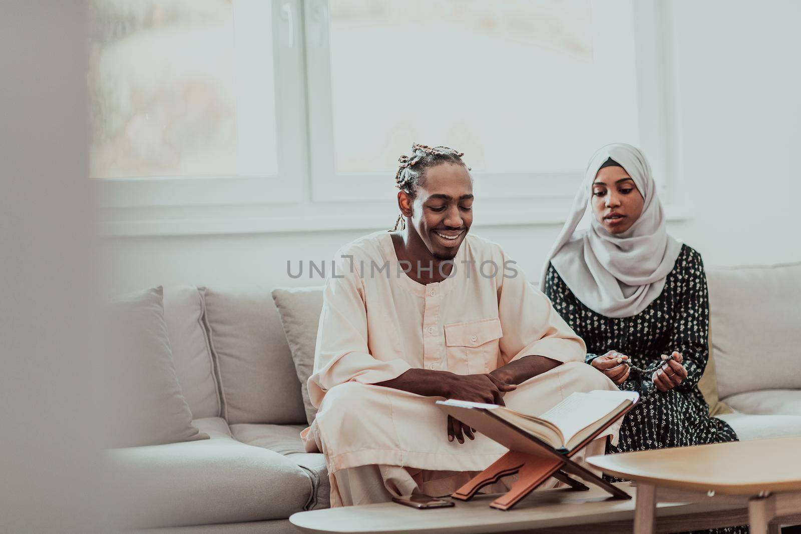 African Muslim couple at home in Ramadan reading Quran holly Islam book. by dotshock