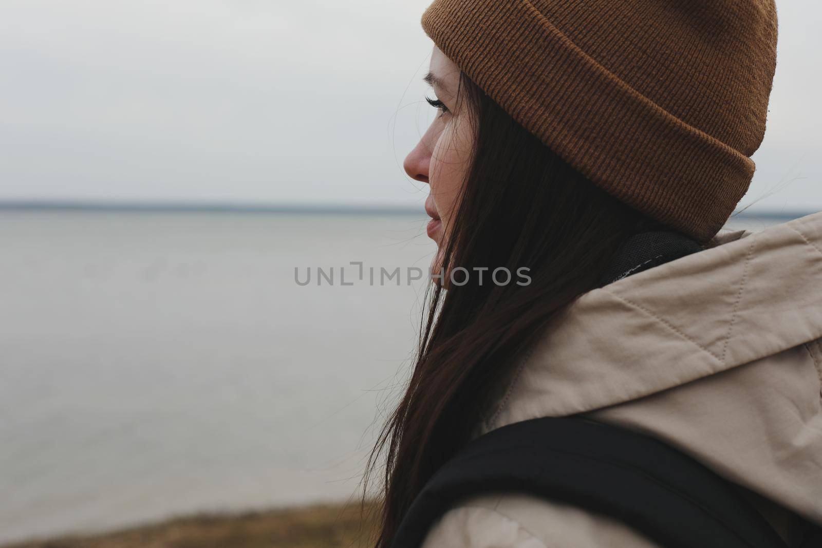 Portrait of young woman in a hat looking over the sea or the ocean, enjoying amazing nature, feeling of freedom. Female traveler