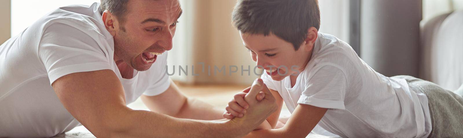 Happy man enjoying active time with son indoors by Yaroslav_astakhov