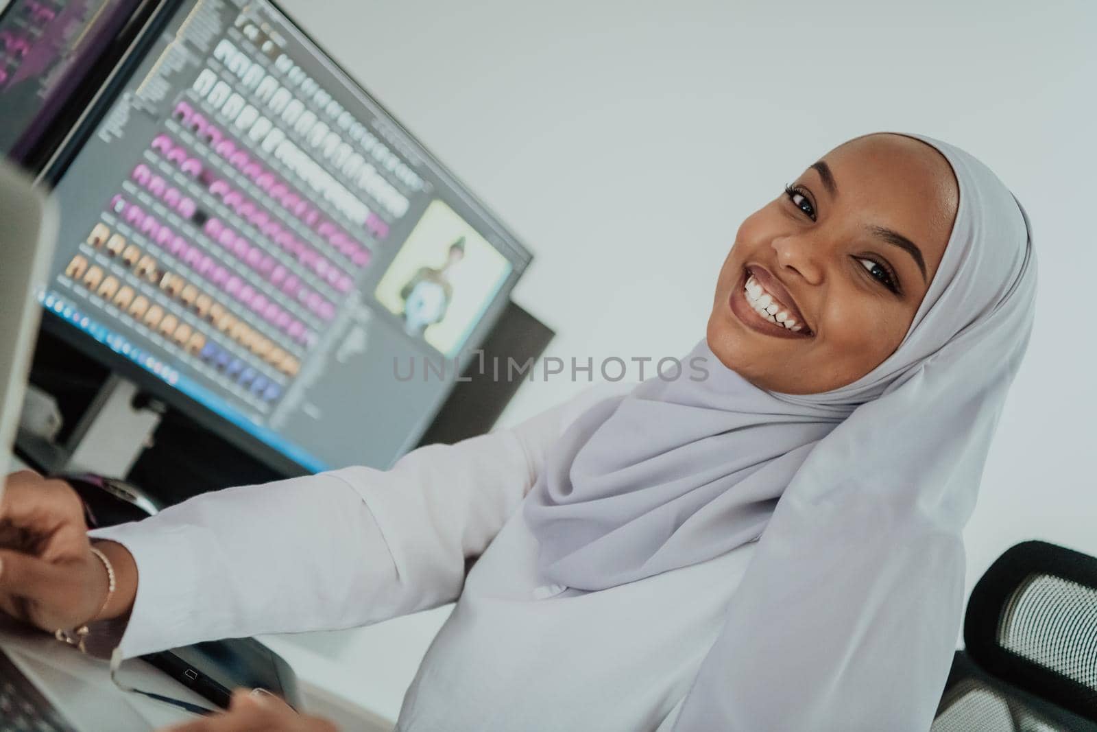 Young Afro-American modern Muslim businesswoman wearing a scarf in a creative bright office workplace with a big screen. High-quality photo