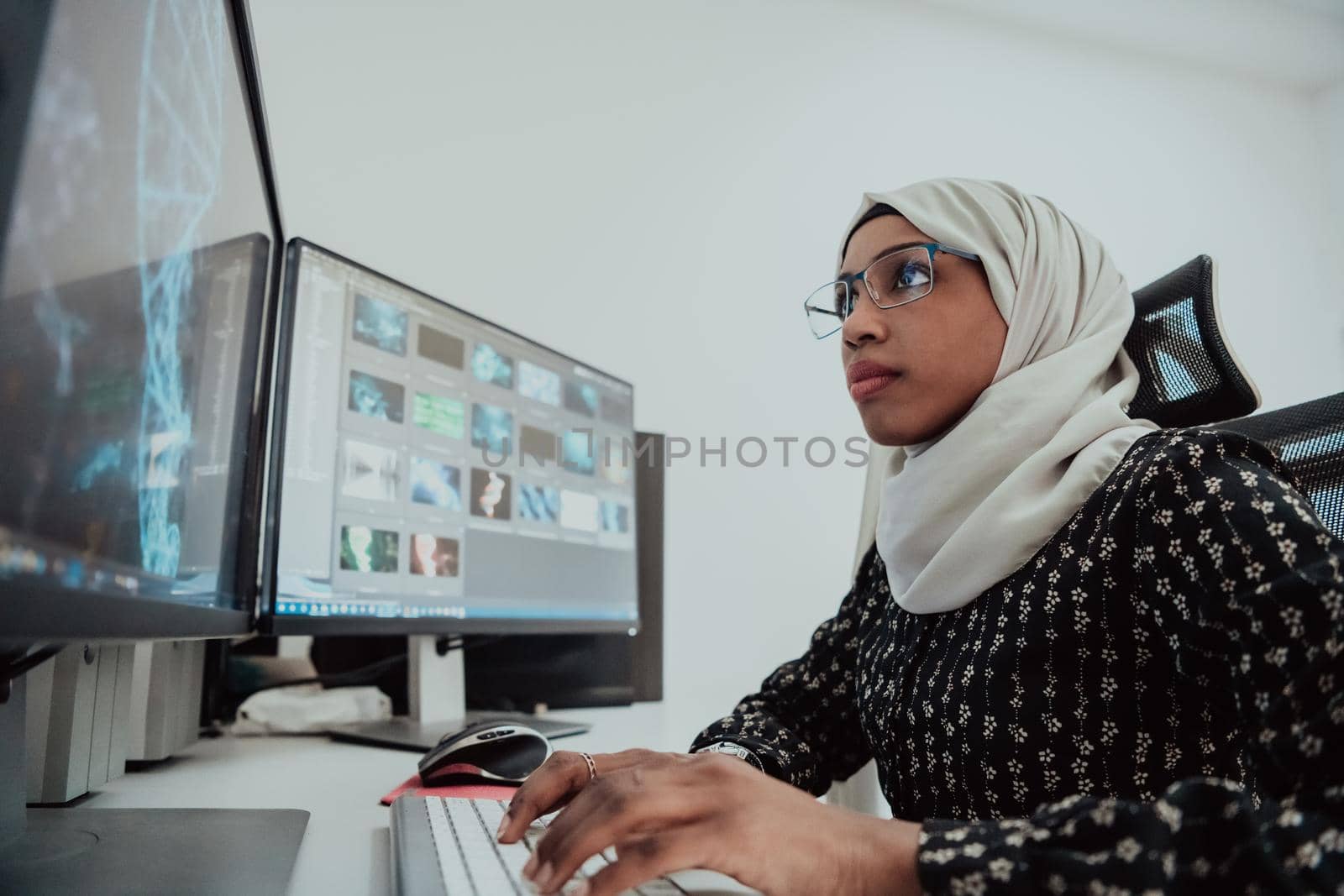 Young Afro-American modern Muslim businesswoman wearing a scarf in a creative bright office workplace with a big screen. High-quality photo