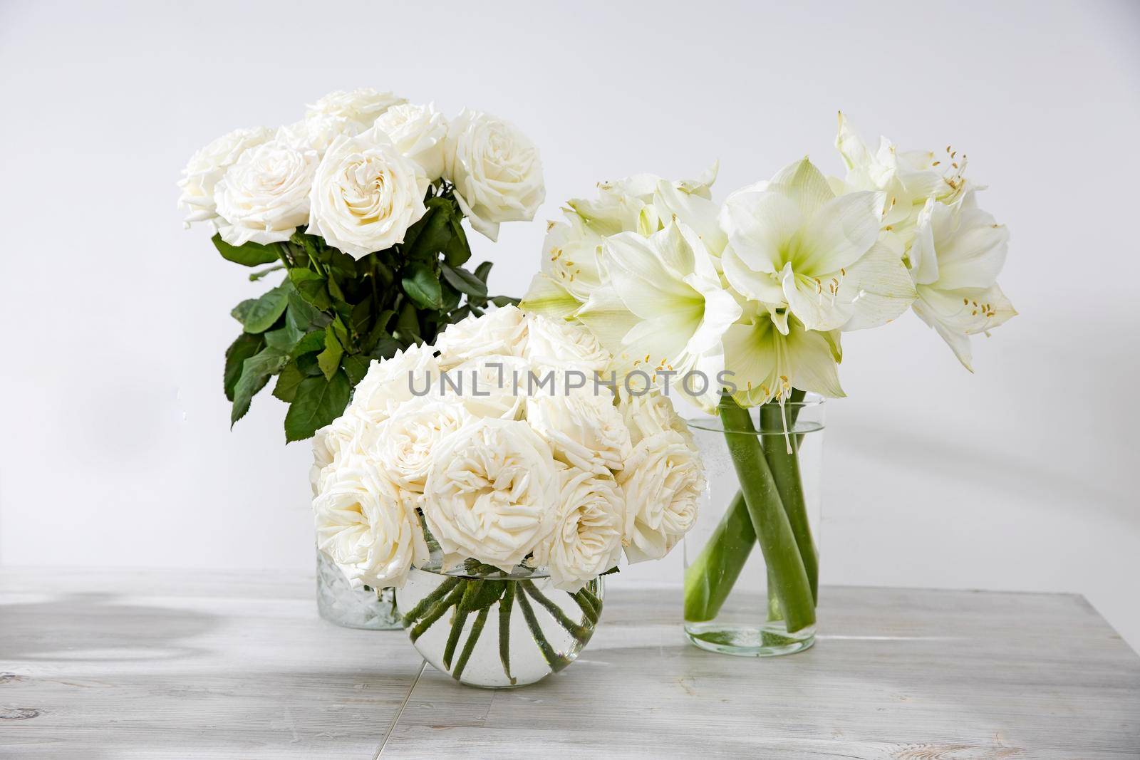 White roses, lily in round vases on the table for a special occasion as a kitchen decoration. Copy space